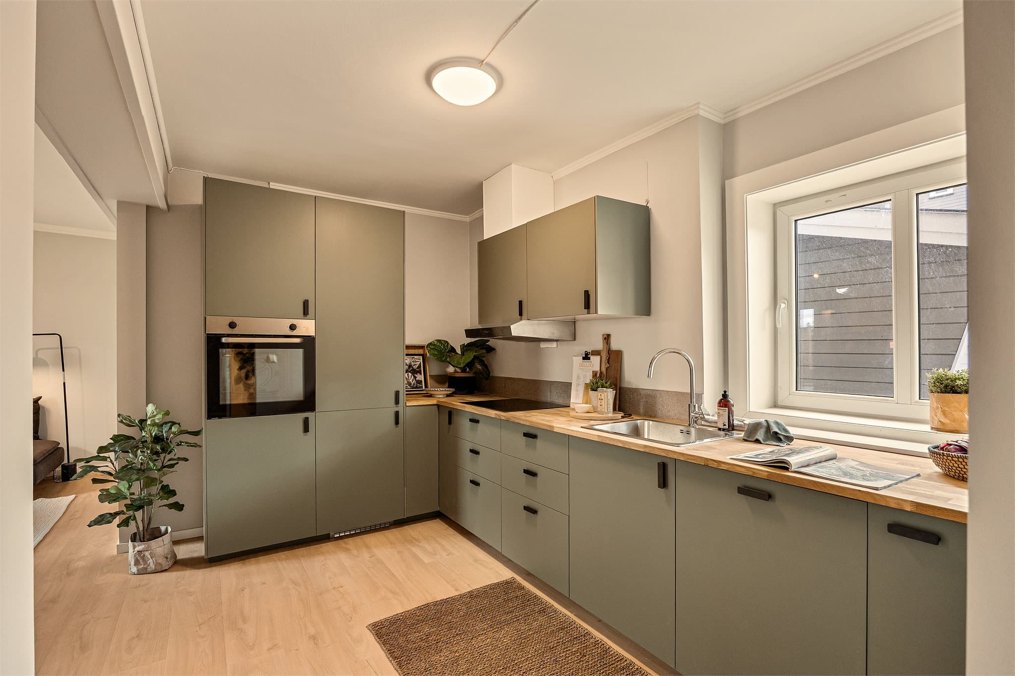 Moderne kjøkken med slette fronter, overskap og heltre benkeplate med nedfelt stålkum.