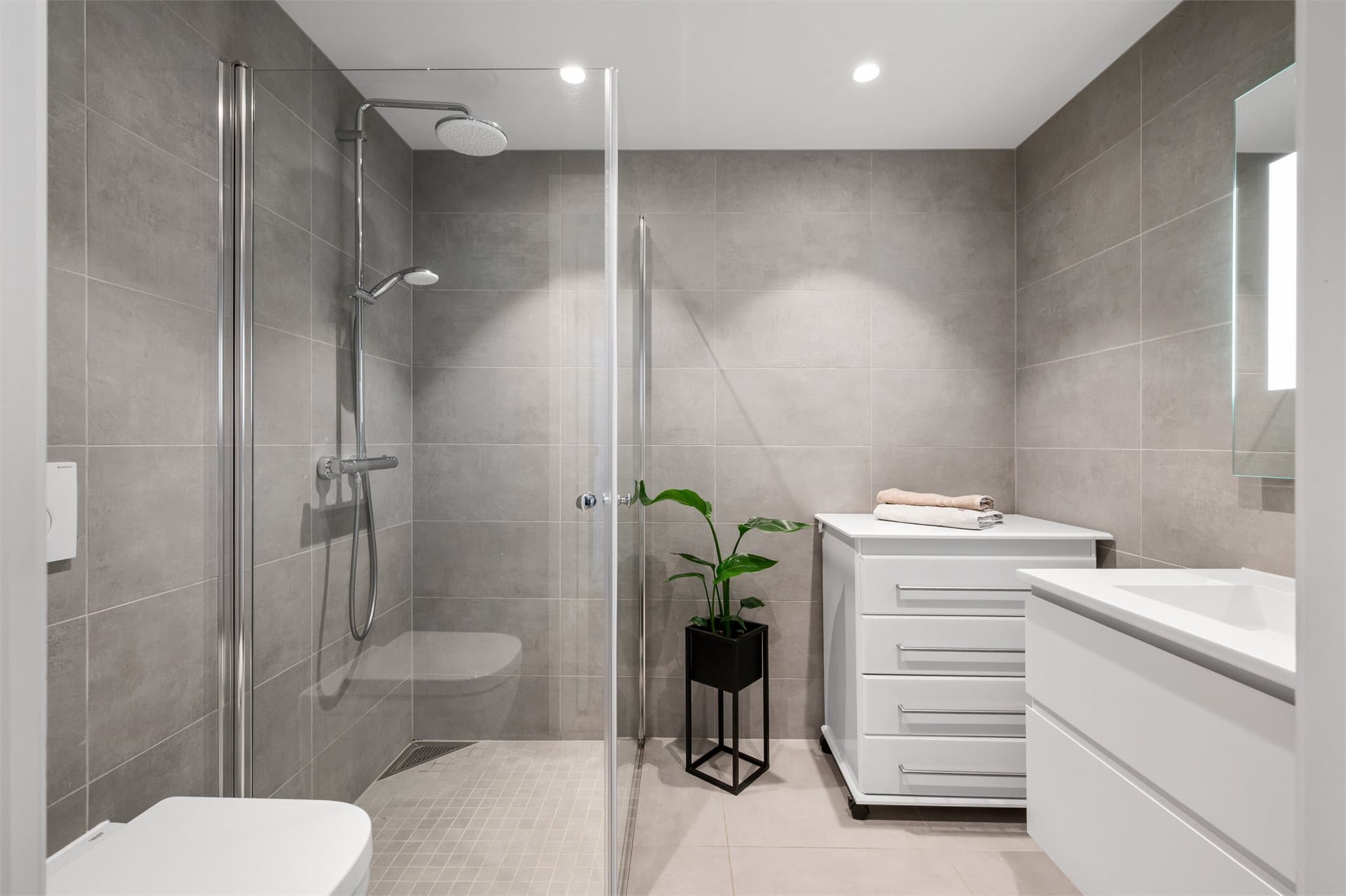 - Bad 2 måler 4,1 m² og er innredet med vegghengt toalett, dusjdører i glass og benkeskap med servant -