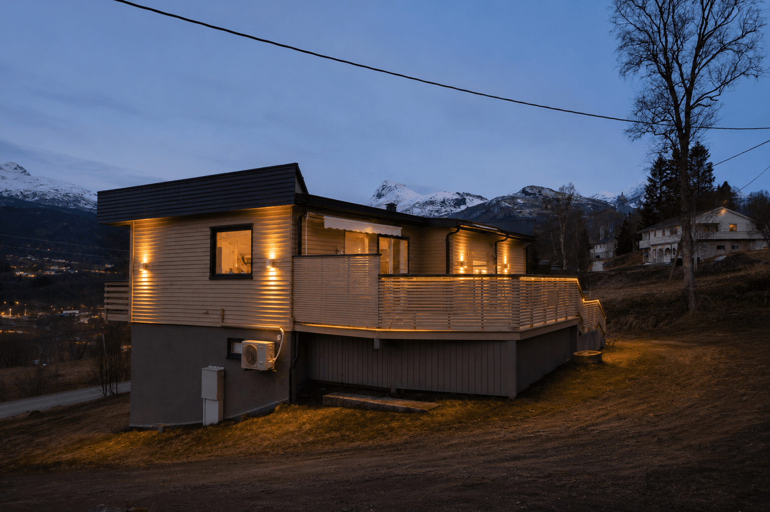 Gjennomført belysning av fasade, veranda og rekkverk skaper en varm og innbydende ramme rundt boligen - en stemningsfull uteplass som kan nytes året rundt. (AI-generert kveldsbilde)