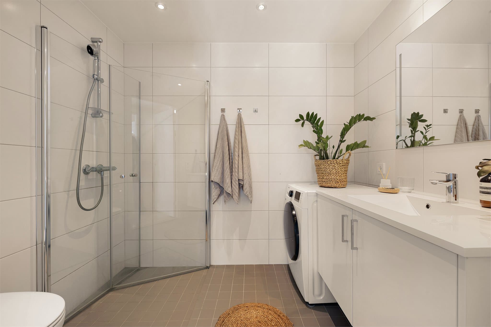 Badet er en prefabrikkert baderomskabin med flislagte overflater, downlights i himling og opplegg for vaskemaskin.