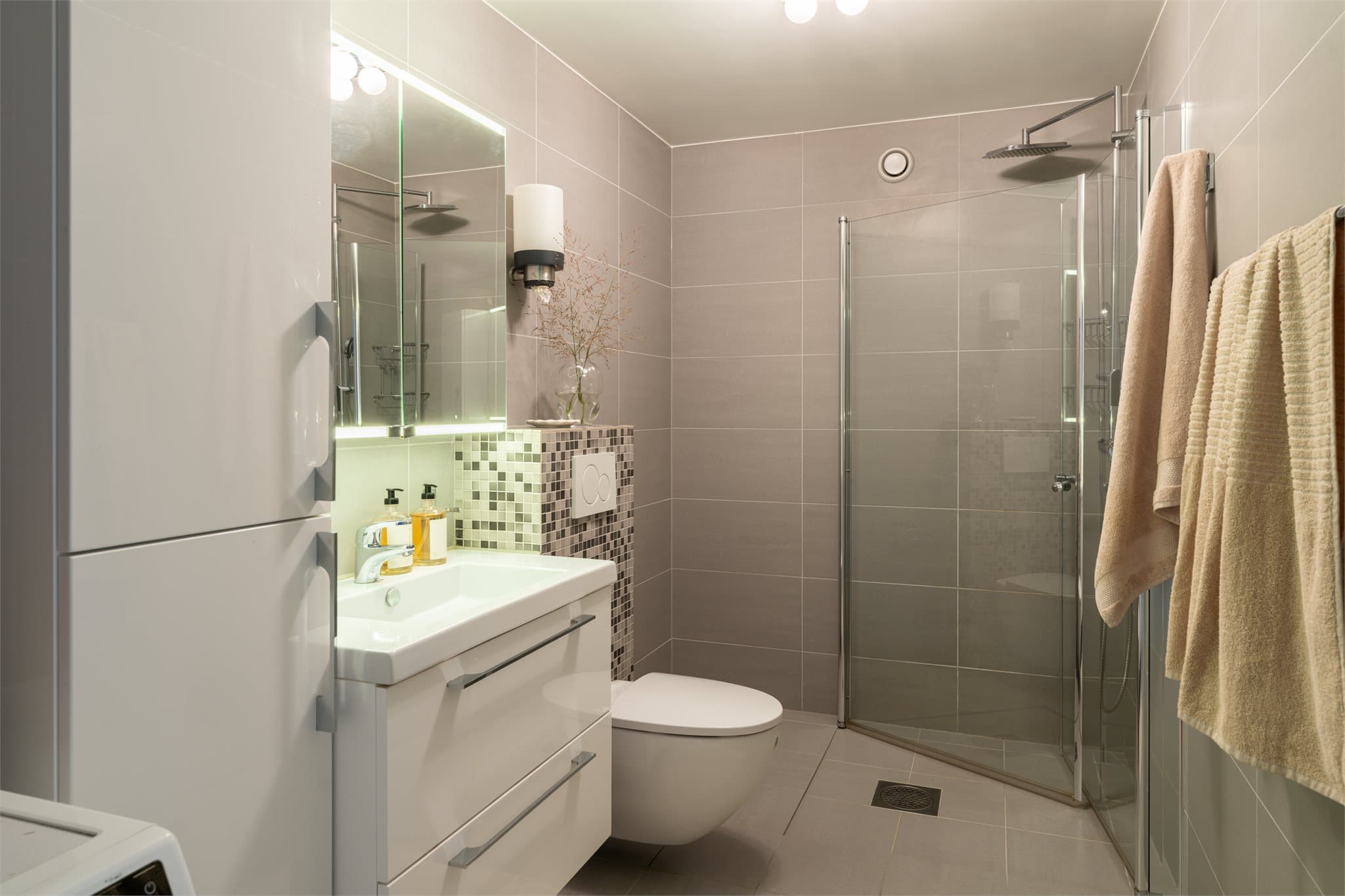 Flislagt bad fra 2016 med gulvvarme, vegghengt toalett og dusjhjørne med glassvegger.