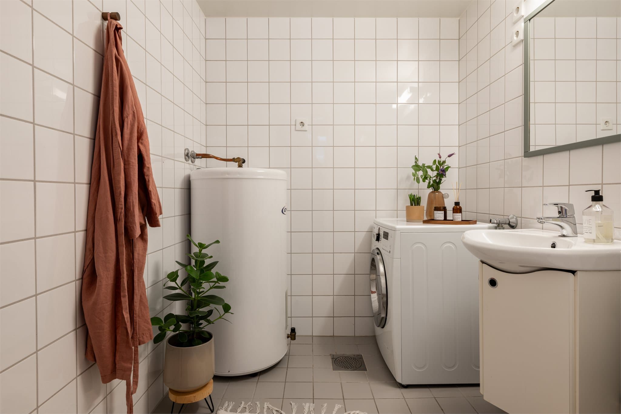 Rommet har flislagt gulv med varmekabler, opplegg for vaskemaskin og en 200L varmtvannsbereder.