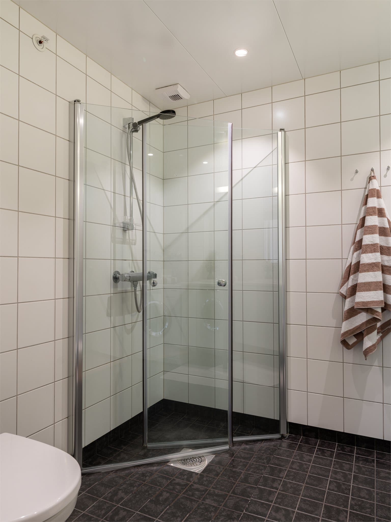 Videre har badet en romslig dusjnisje bak innfellbare dører i herdet glass.