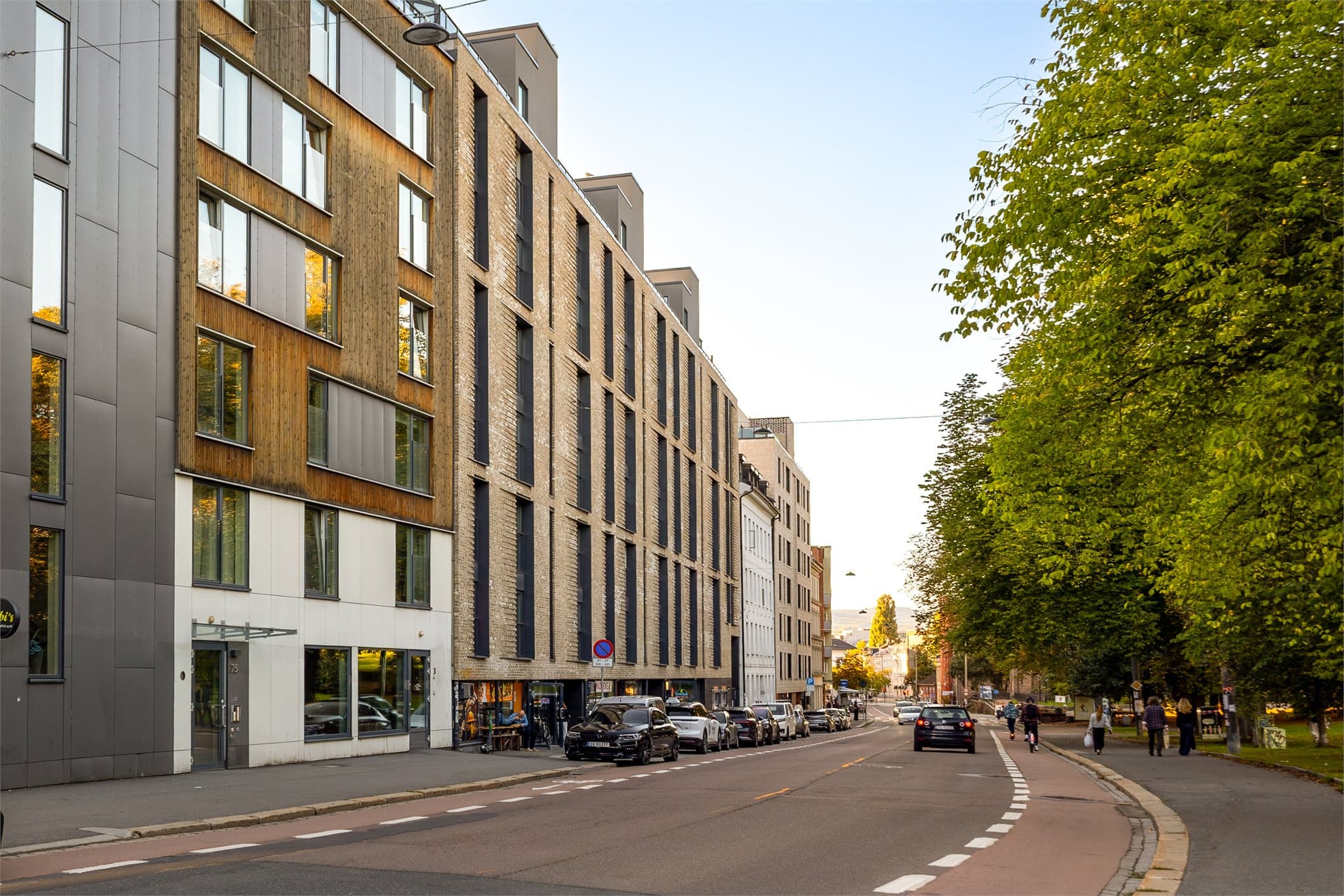 Teglsteinsfasaden mot Grønlandsleiret med butikker på bakkeplan og heisadkomst.