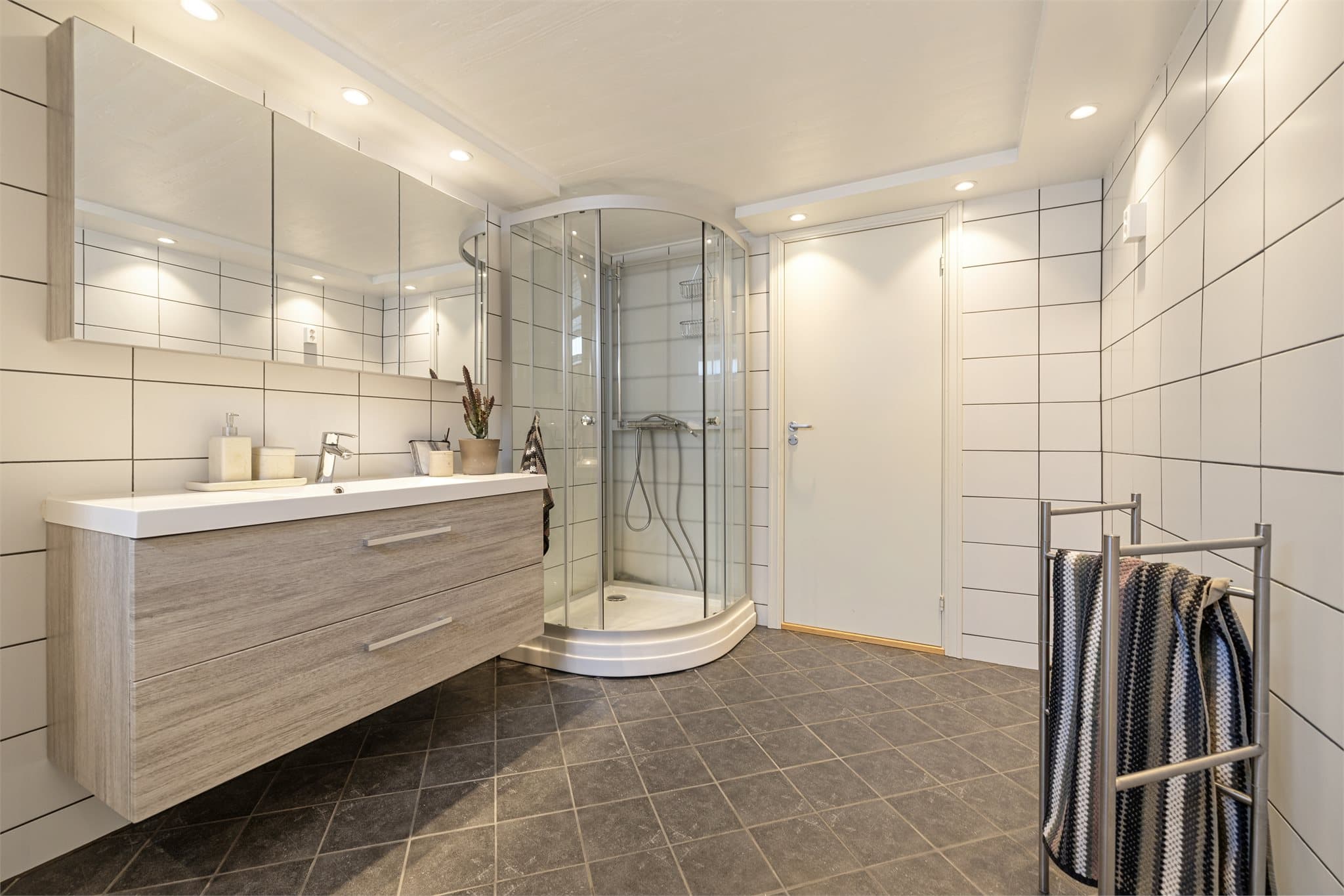 Her finner du dusjkabinett med skyvedører, gulvmontert toalett, servantskap med speilskap og gulvvarme. Badet har mekanisk avtrekksventilasjon.