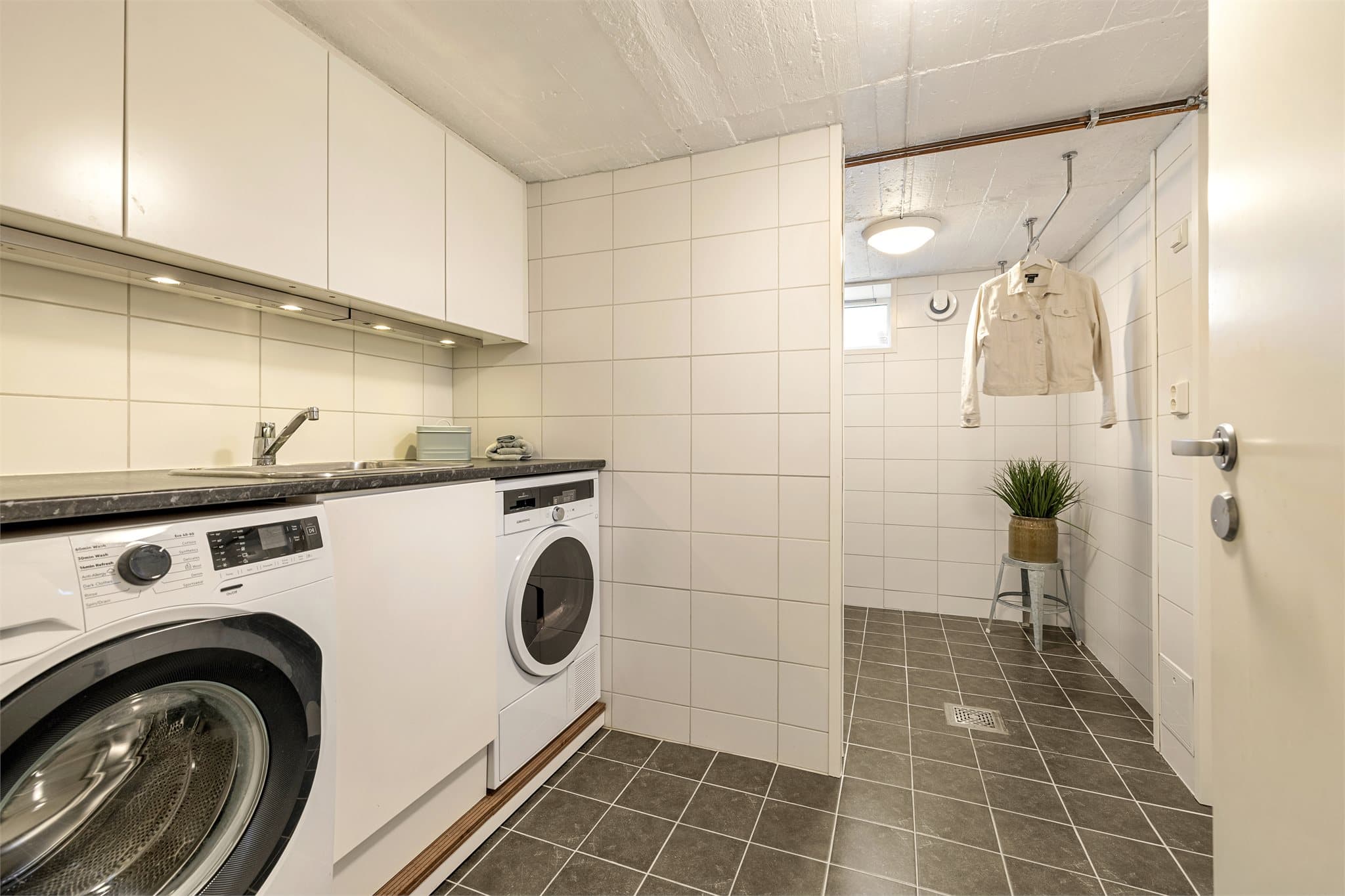 askerommet i underetasjen ble oppgradert i 2017. Det har flislagt gulv og vegger, gulvvarme, opplegg for vaskemaskin og tørketrommel samt innredning med underskap, overskap og høyskap med glatte fronter. Her er også varmtvannsbereder på 287 liter fra 2017