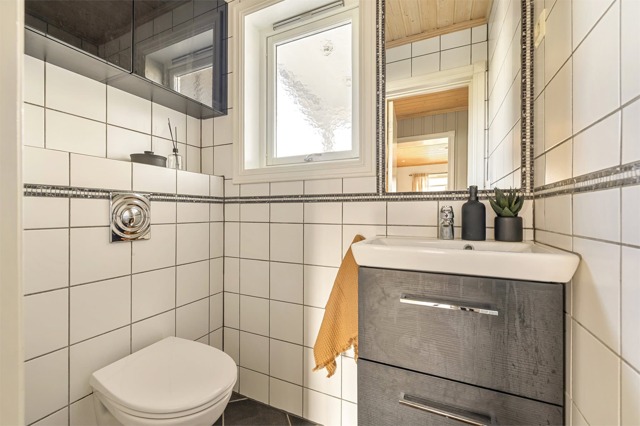 Toalettrommet i 1. etasje er fra 2003 og har flislagt gulv med varmekabler, fliser på vegg og veggmontert toalett.