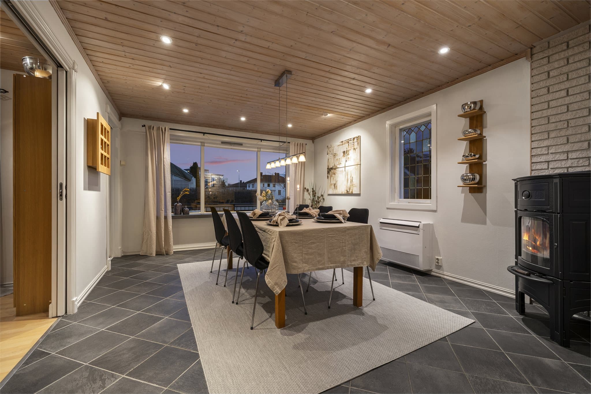 Videre fra kjøkkenet kommer du inn til en koselig spisestue med en frittstående peisovn med glass som skaper en lun og innbydende atmosfære