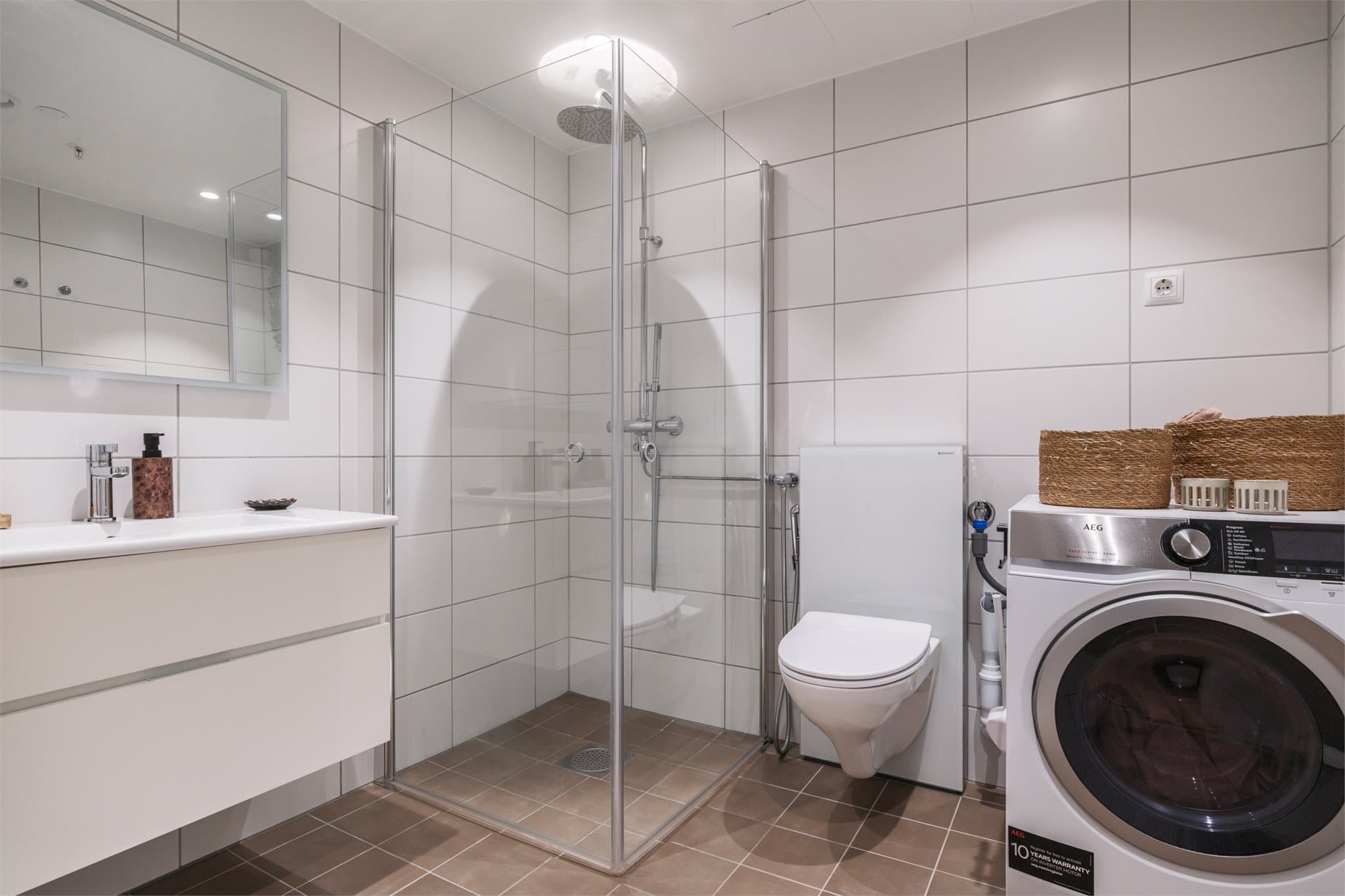 Fra gangen er det direkte adkomst til et delikat bad. Badet har mørke 20x20 fliser på gulv med varme og hvite 25x40 fliser på vegger. Badet er innredet med lys baderomsinnredning med speil med lys over, innfellbare dusjvegger og innebygd toalett.