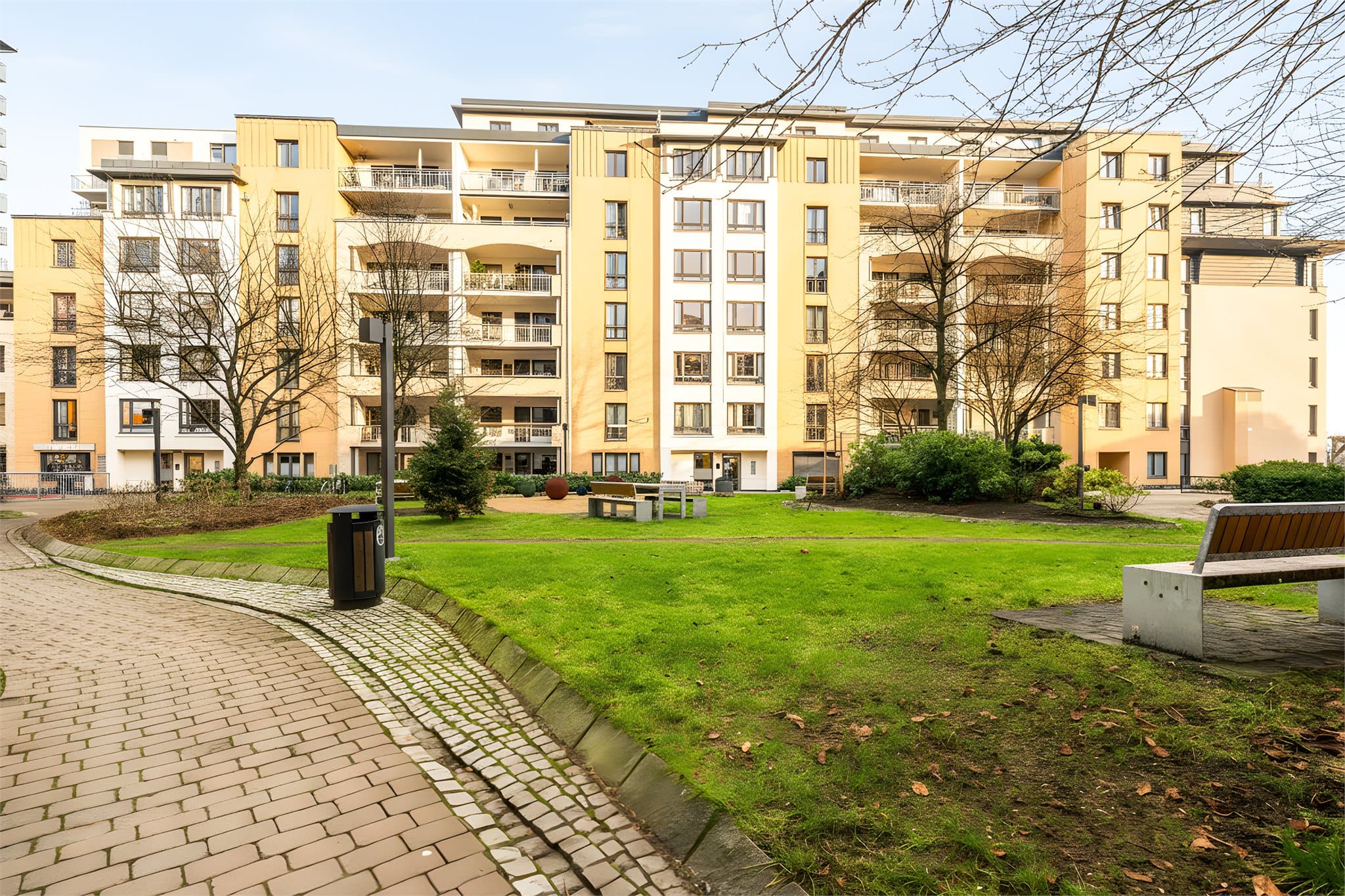Nydelig og velholdt bakgård, opparbeidet med asfalterte gangveier, planter, busker og trær. Sittegrupper, lekeapparat og utegrill.
