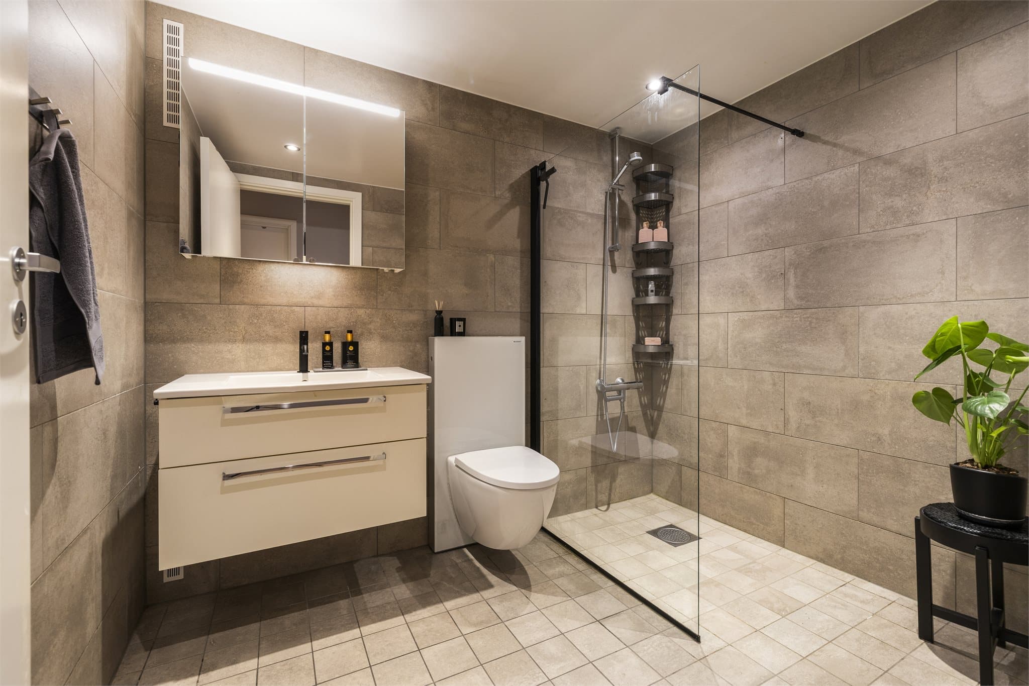 Helflist bad med termostatstyrt gulvvarme, downlights og et romslig dusjhjørne med glassfelt.