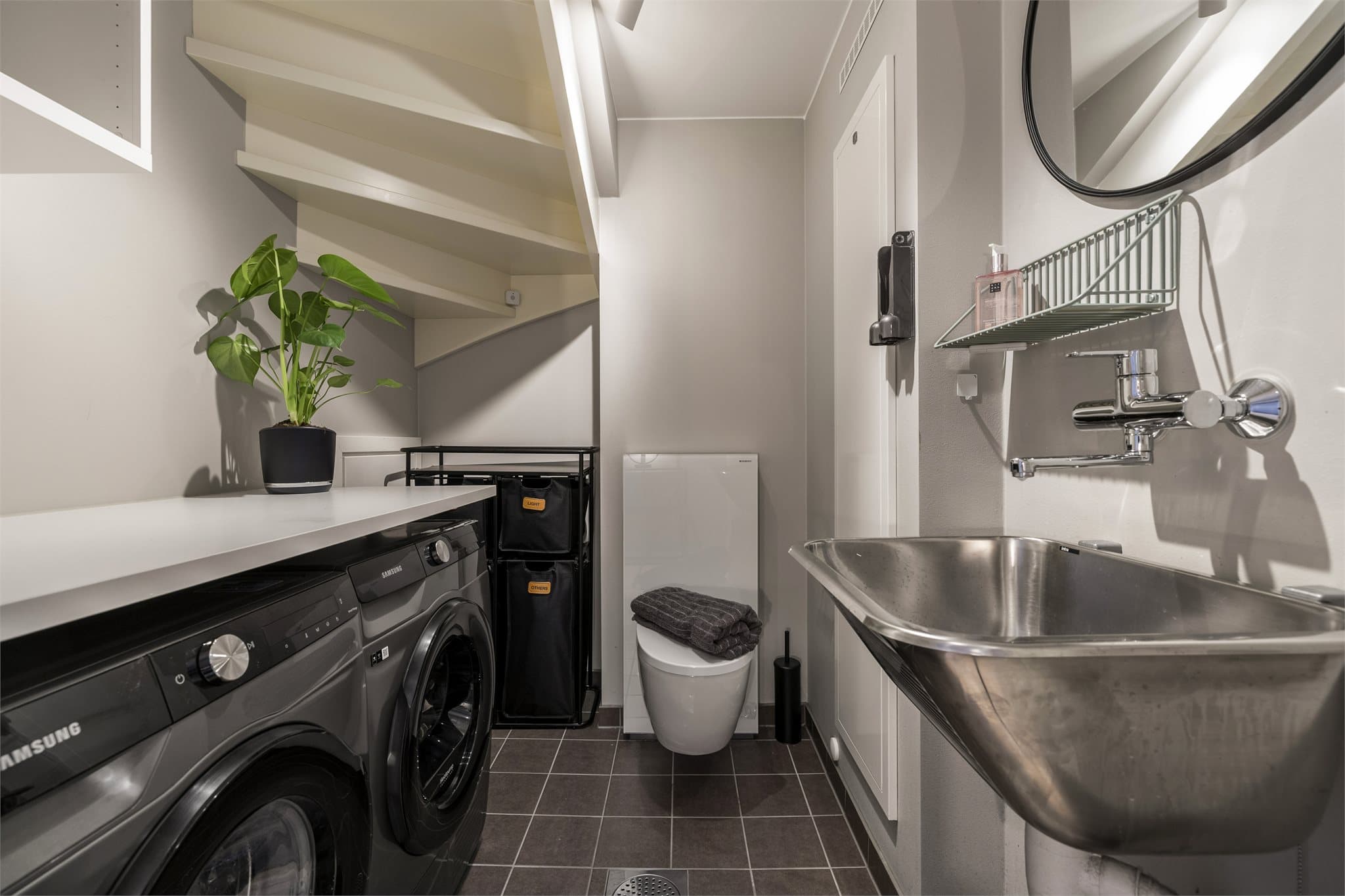 Separat toalett og vaskerom med opplegg for vaskesøyle og praktisk benkeplate.