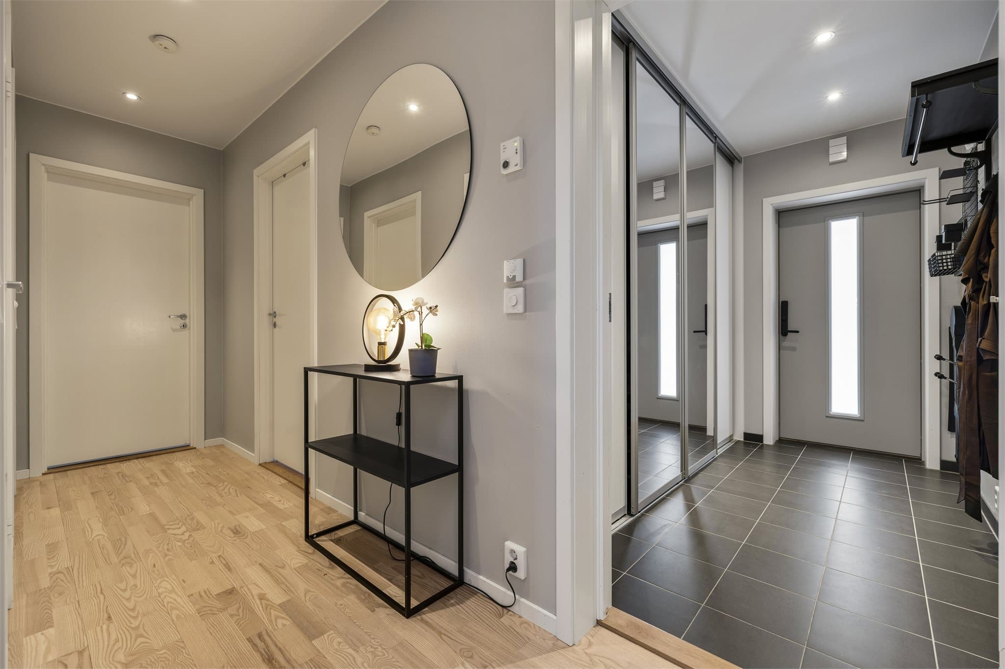 Innbydende entré med flislagt gulv og en romslig skyvedørsgarderobe med speilfronter.