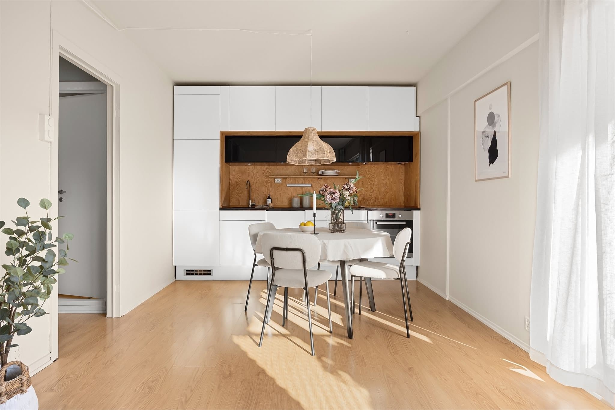 Kjøkkenet har en stilren og moderne innredning med glatte, hvite fronter kombinert med varme tredetaljer.