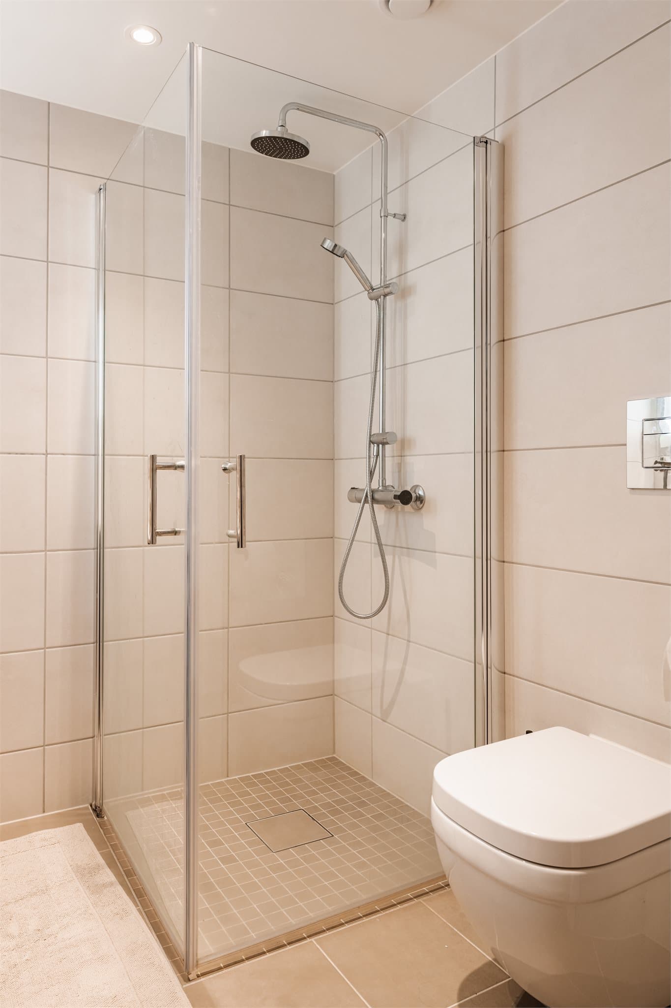 Badet er også utstyrt med vegghengt toalett og dusjhjørne med svingbare glassdører.