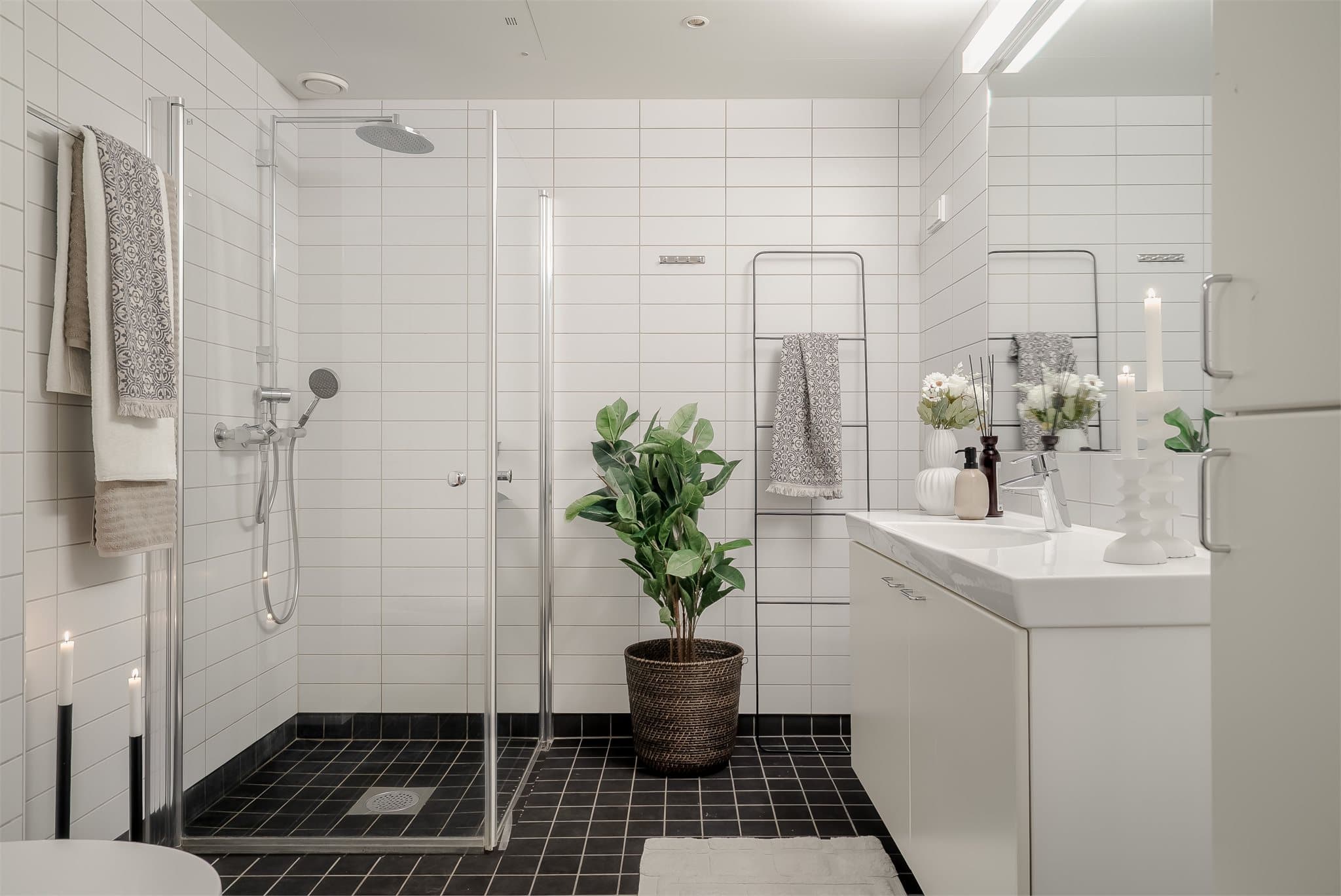 Lyst og romslig baderom utstyrt med dusjhjørne, servantinnredning og toalett.