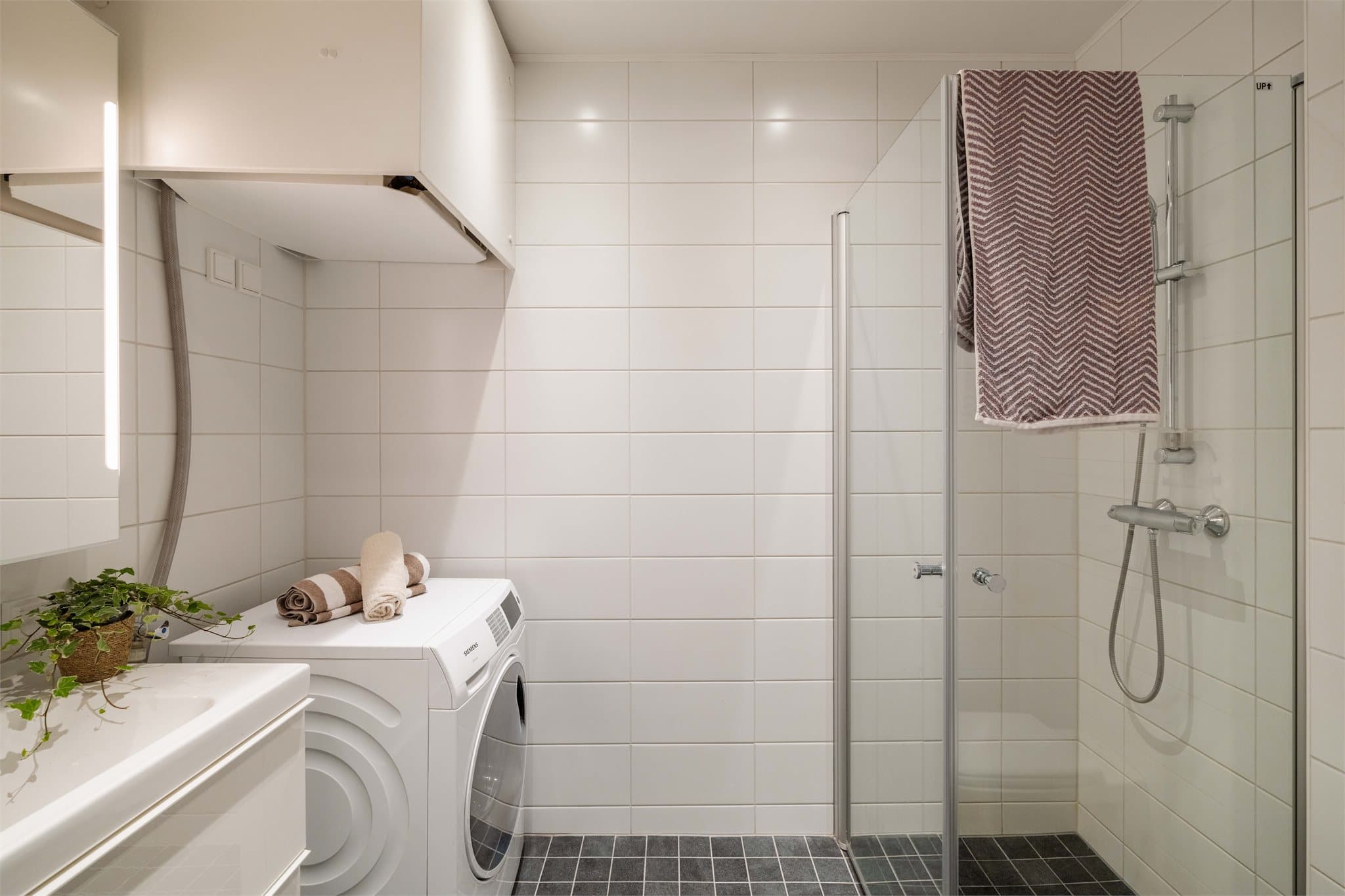 Pent, helfliset baderom med gulvvarme. Badet er innredet med servant, klosett og dusjhjørne med innfellbare glassdører.