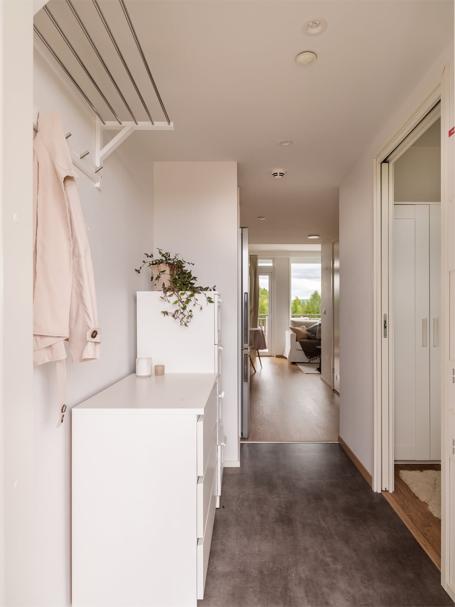 Leiligheten har en lys og innbydende entré med lysmalte vegger og parkett på gulv.