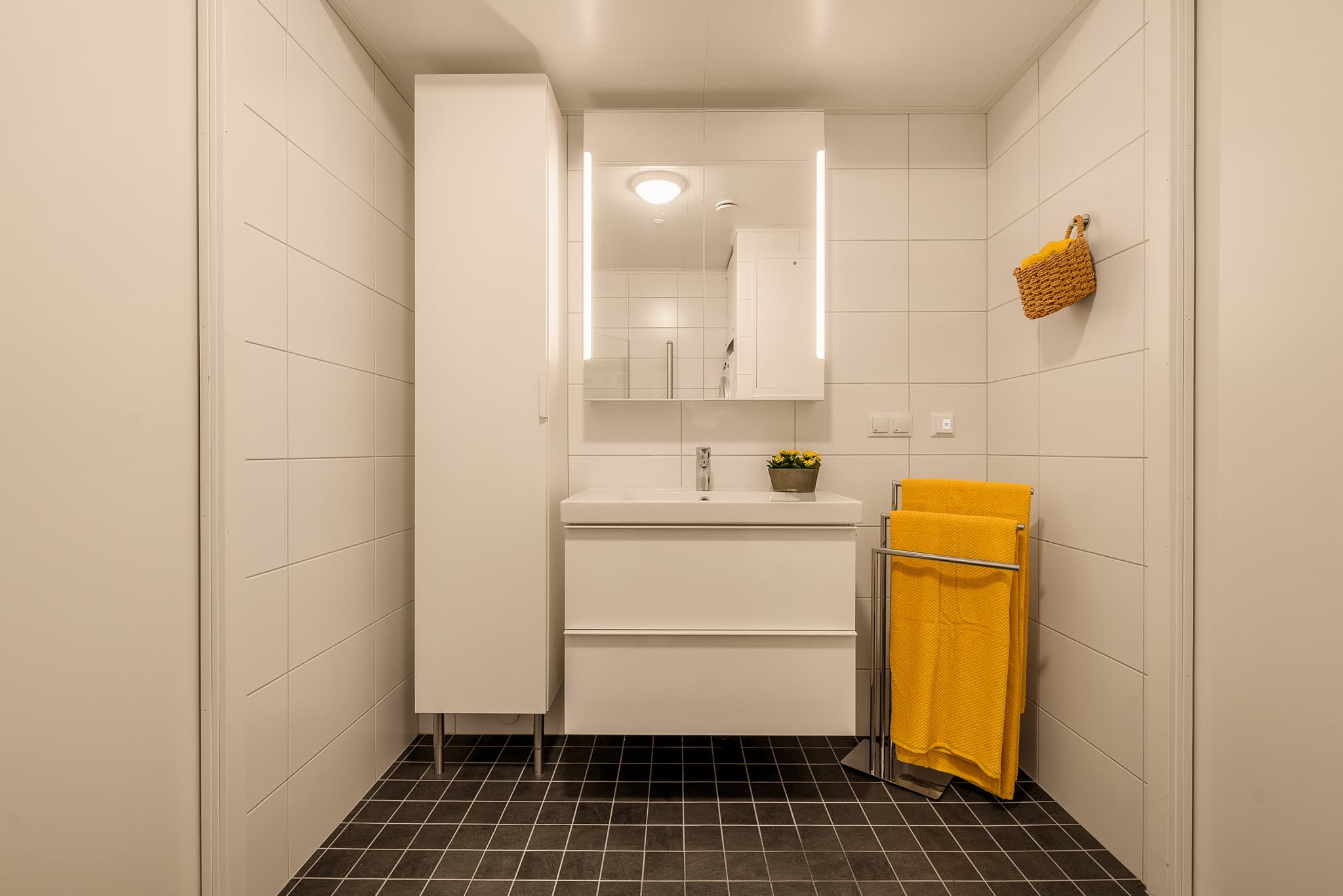 Badet er innredet med helservant på skuffeseksjon, speilskap med belysning og høyskap.