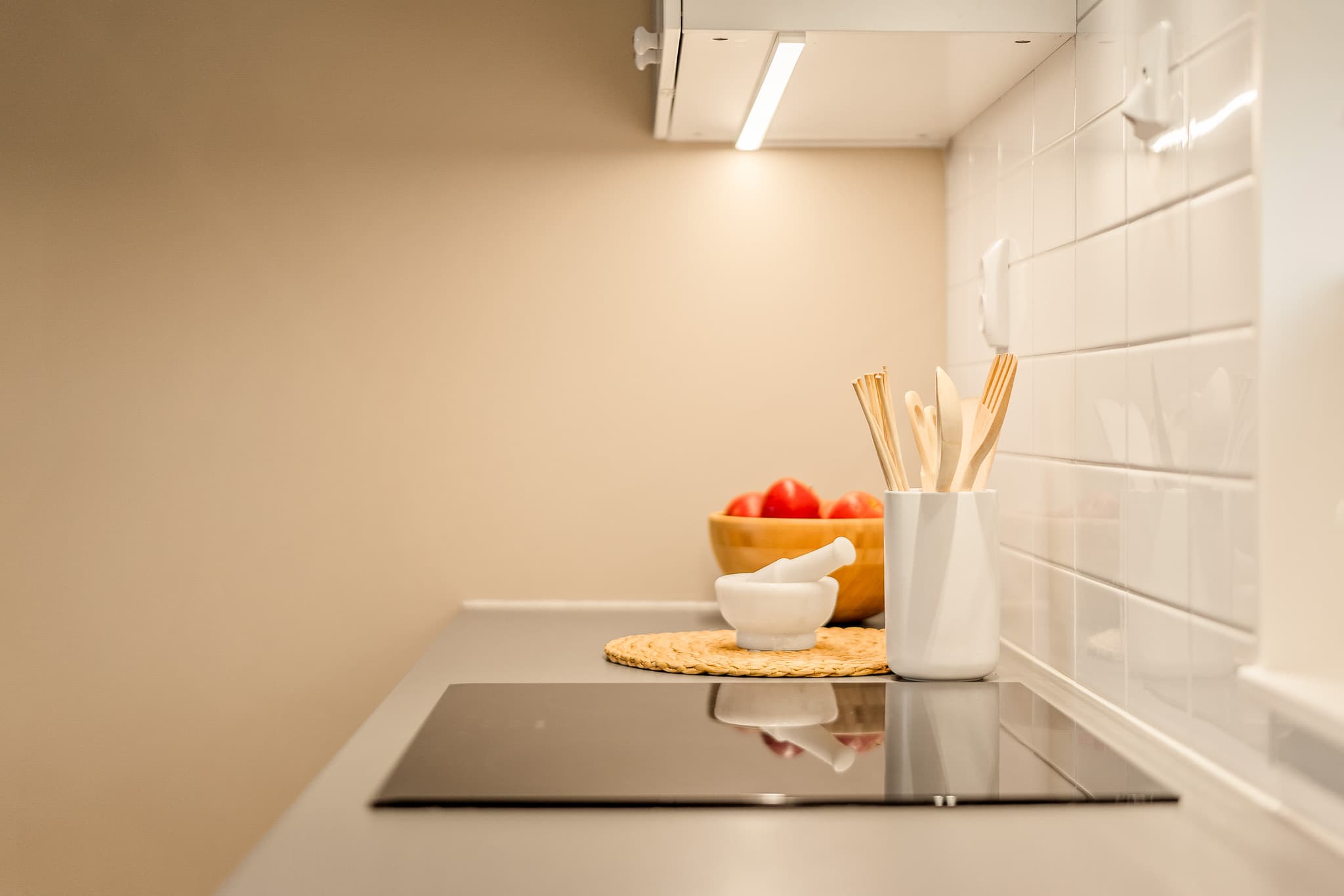 Mellom benk og overskap er det fliser og det er montert komfyrvakt.