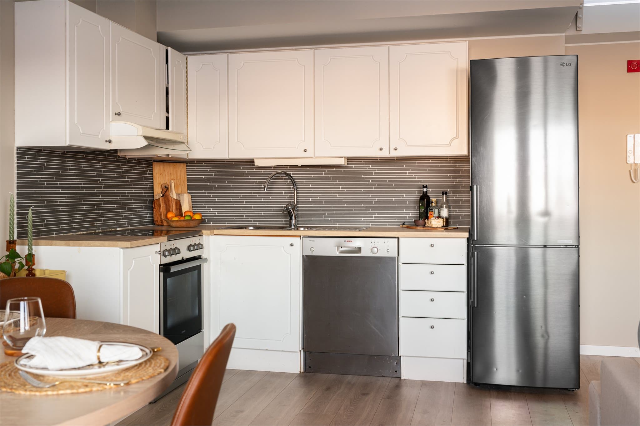 Lys innredning med profilerte, fabrikklakkerte fronter og benkeplate i laminat med nedfelt kum i rustfritt stål.