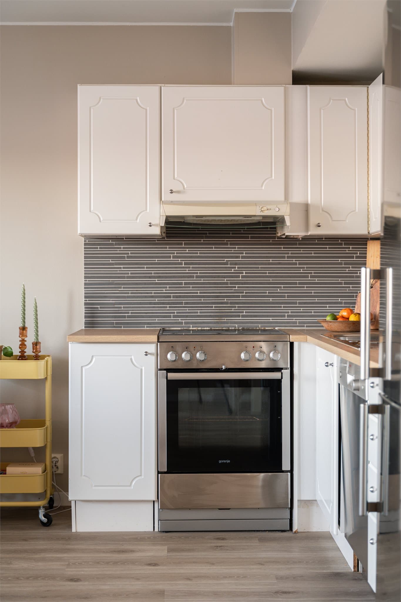 Videre er det fliser over benkeplate og belysning under overskap.