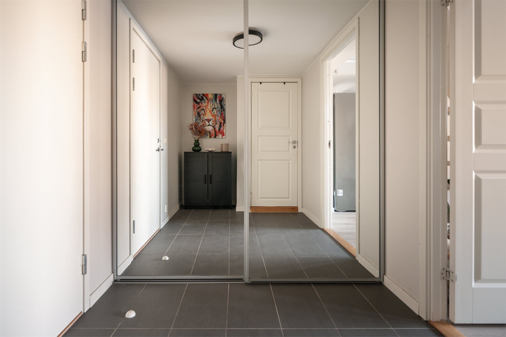 Du ønskes velkommen inn av en lysmalt entrè med flislagt gulv, hvor man kan henge fra seg yttertøyet i en praktisk skyvedørsgarderobe med speilfronter.