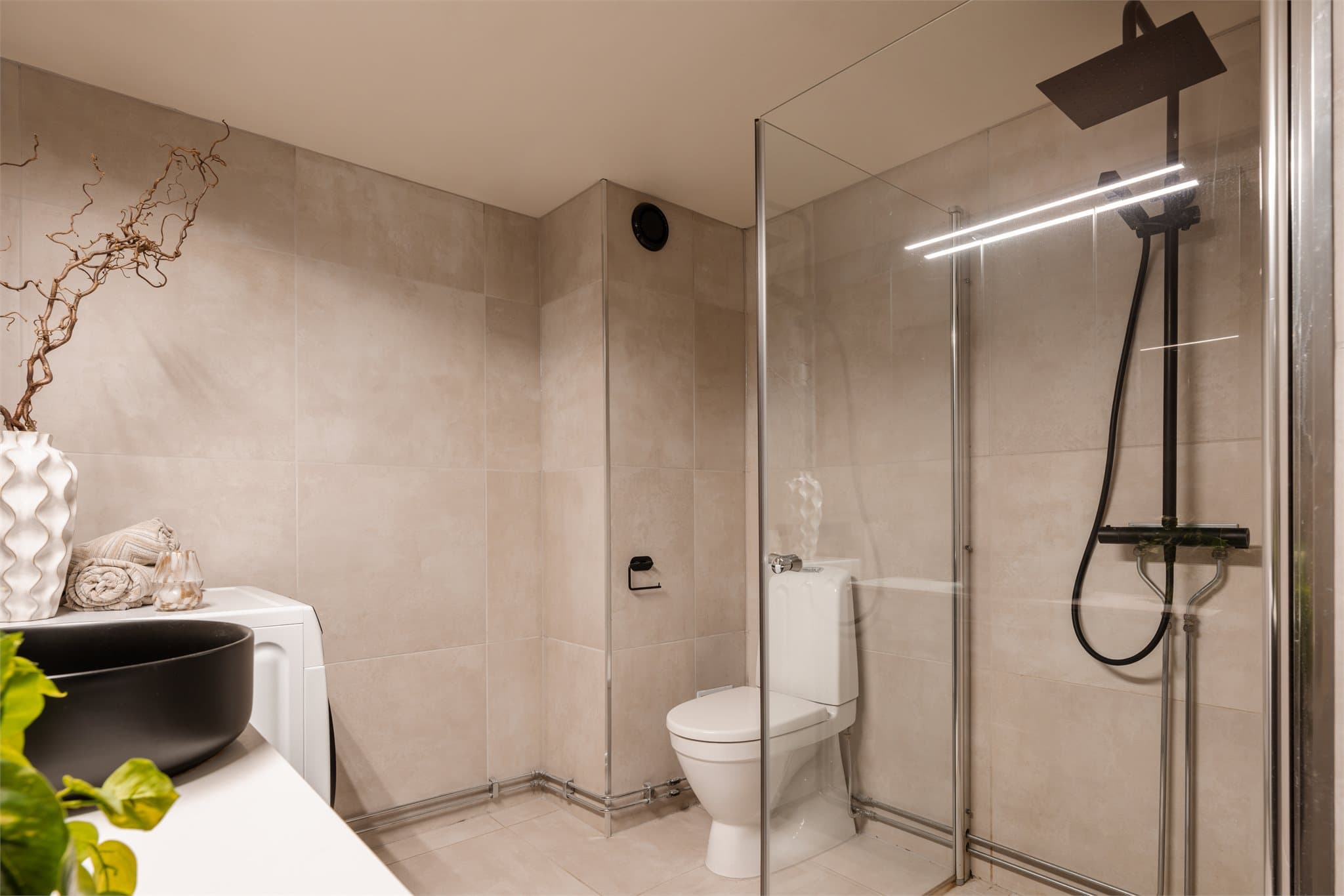 Baderommet fremstår delikat, og er innredet med gulvmontert toalett, servantskap med glatte, folierte fronter og benkeplate med servant bolle.