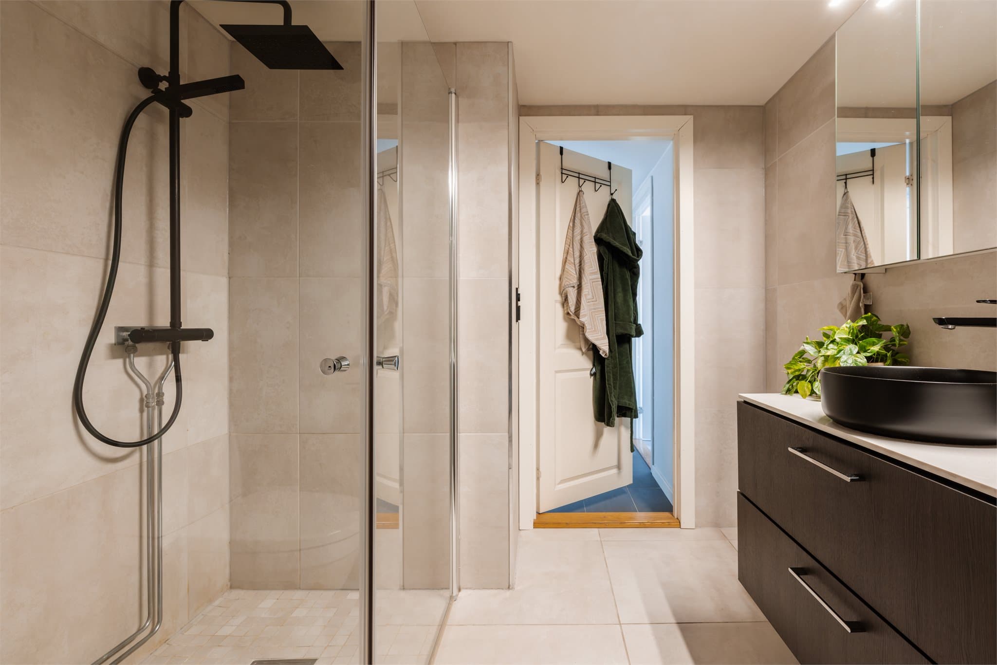 Videre er det speilskap med lysarmatur på vegg over servant og dusjhjørne med svingdører, regnfallsdusj, håndholdt dusj og termostatstyrt blandebatteri. Det er opplegg for vaskemaskin.