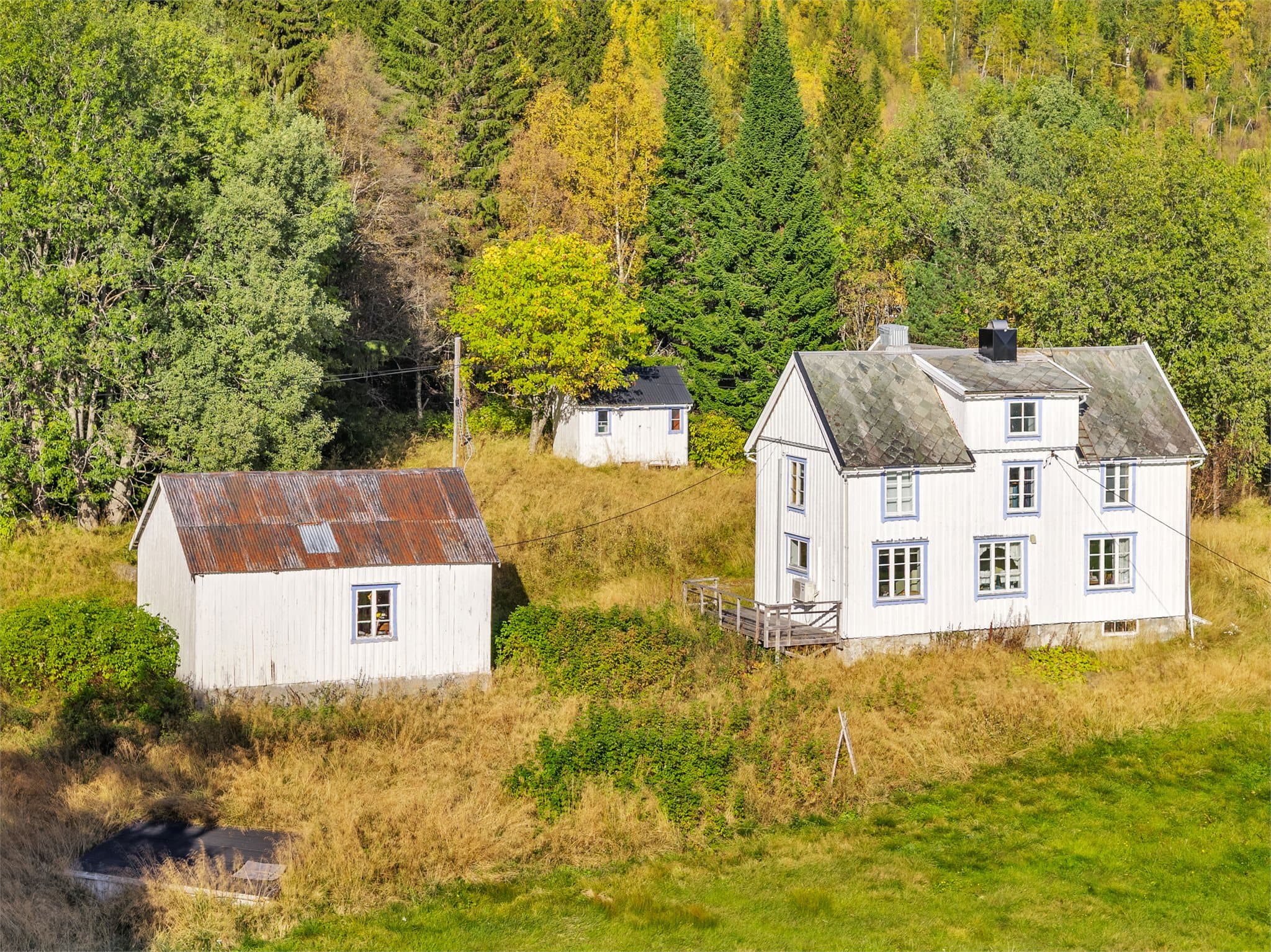 Gårdstunet ligger skjermet til med skogs- og fjellterreng rett bak eiendommen.