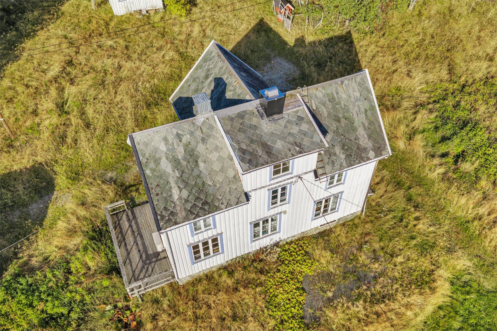 Boligen har taktekking av skifer og utvendig kledning av tømmermannspanel.