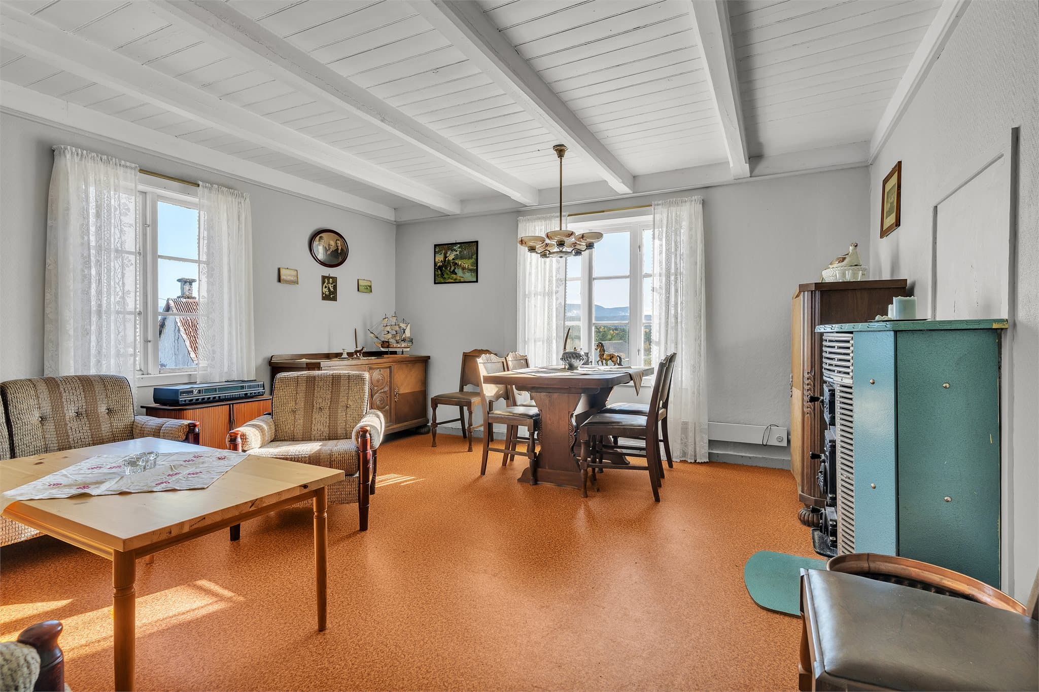 Stuen har synlige takåser og god plass til både sofagruppe og spisebord.