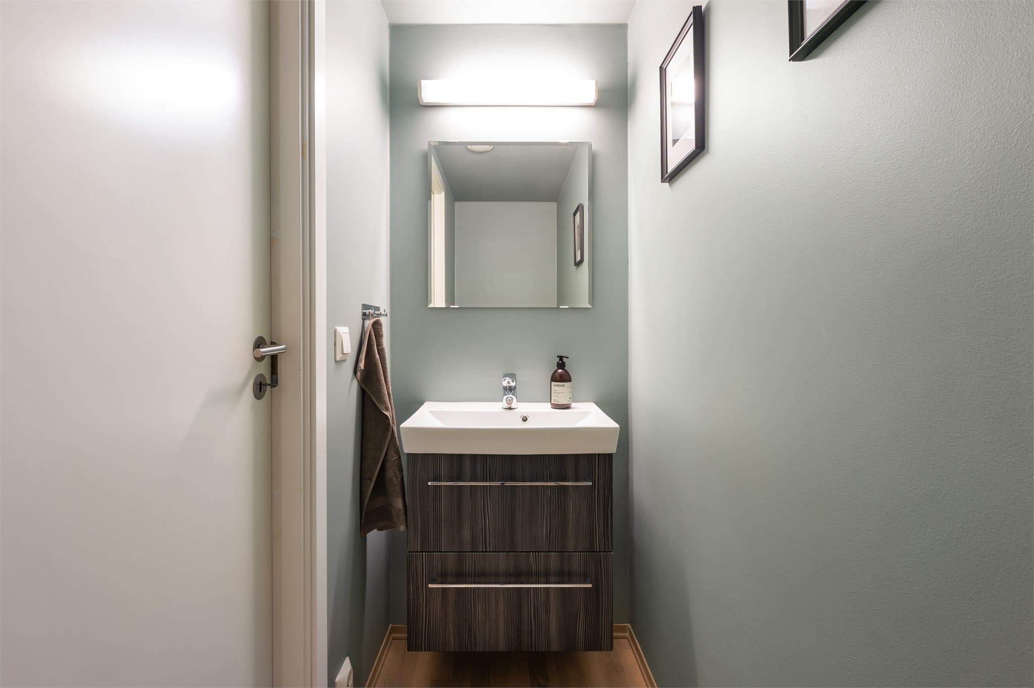 Wc med parkett på gulv og malte flater på vegger og tak. Nyere servant med skuffeinnredning.