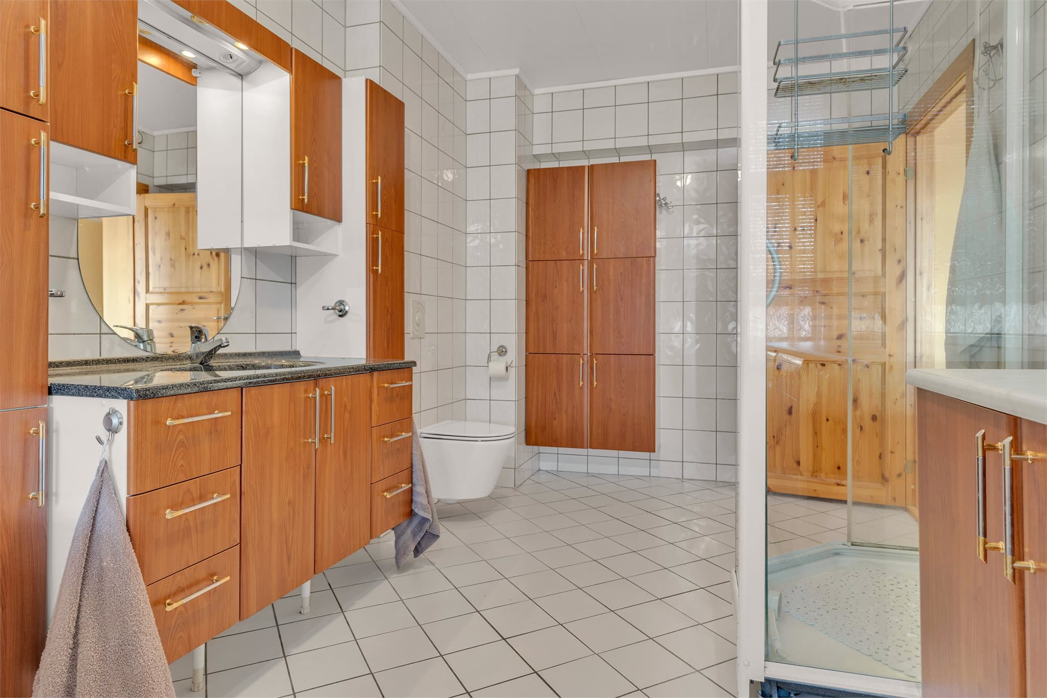 Badet er utstyrt med veggmontert toalett og nedfelt servant.