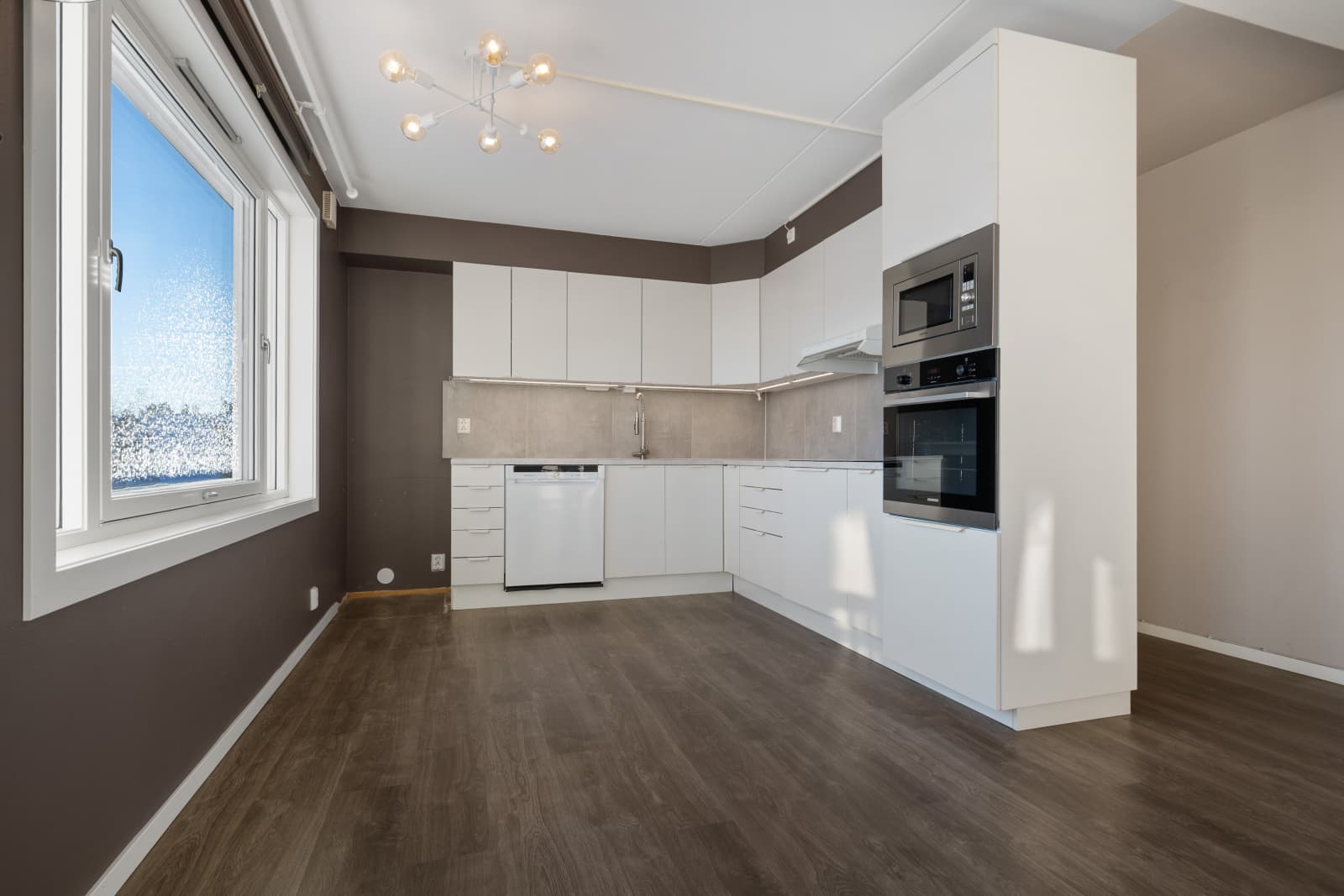 Kjøkkeninnredningen har hvite, slette fronter og laminert benkeplate.