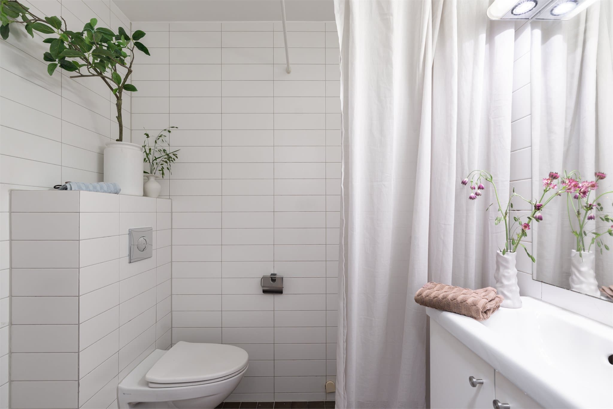 Et flislagt baderom med gulvvarme og vegghengt toalett.