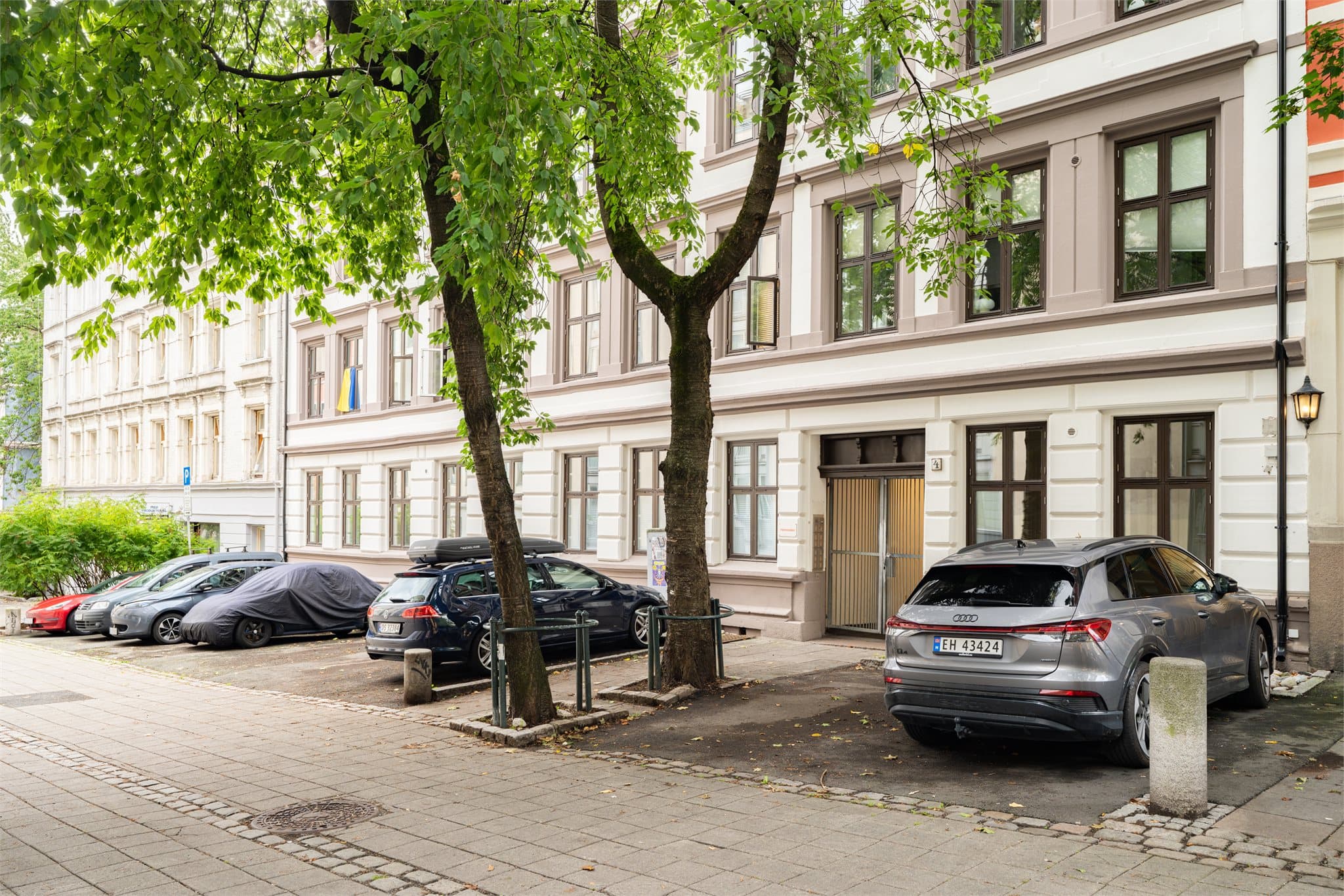 Boligen vender ut mot en rolig gate med flotte trær som gir en grønn utsikt om sommeren.