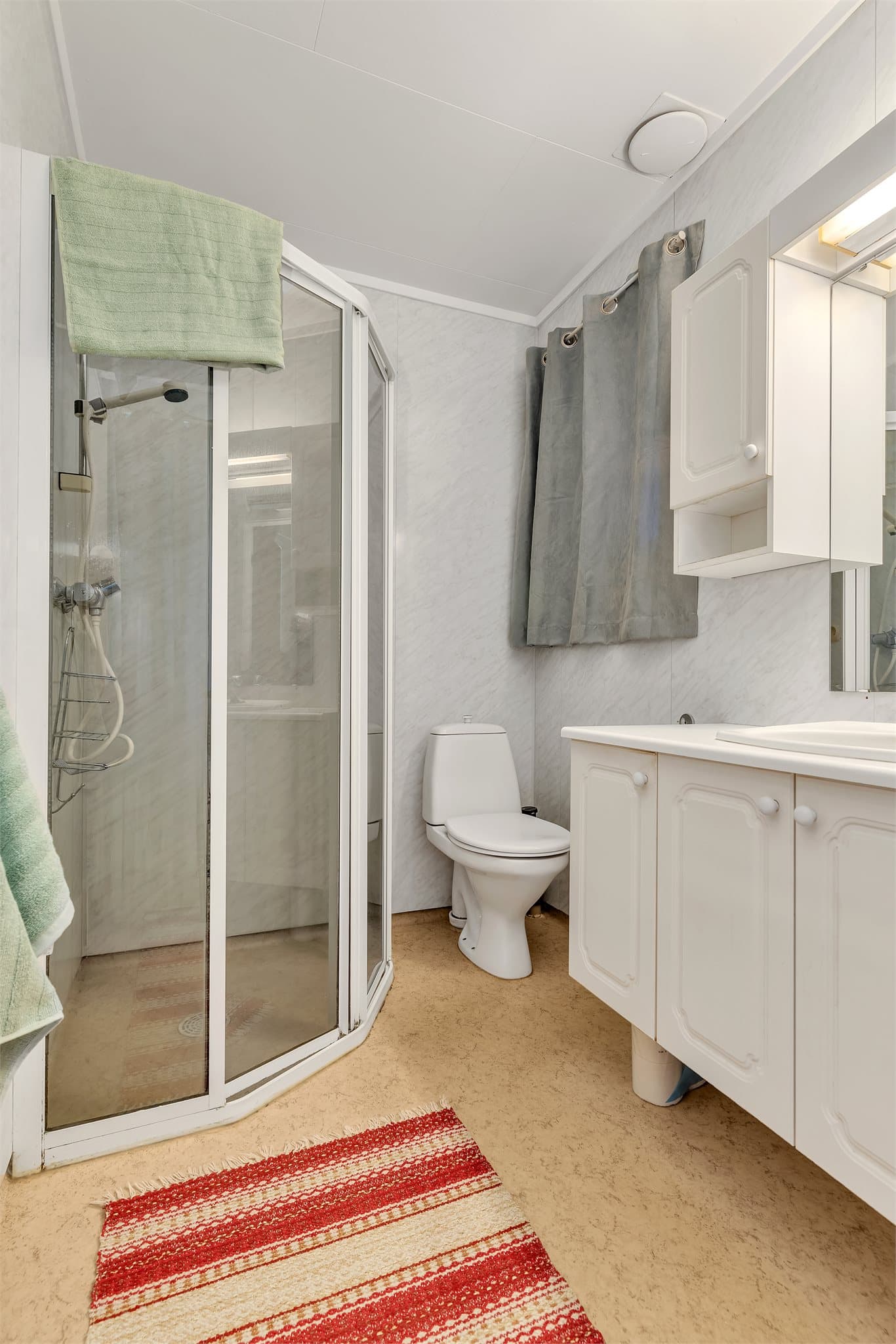 Badet i første etasje er utstyrt med dusjkabinett, servant og toalett.
