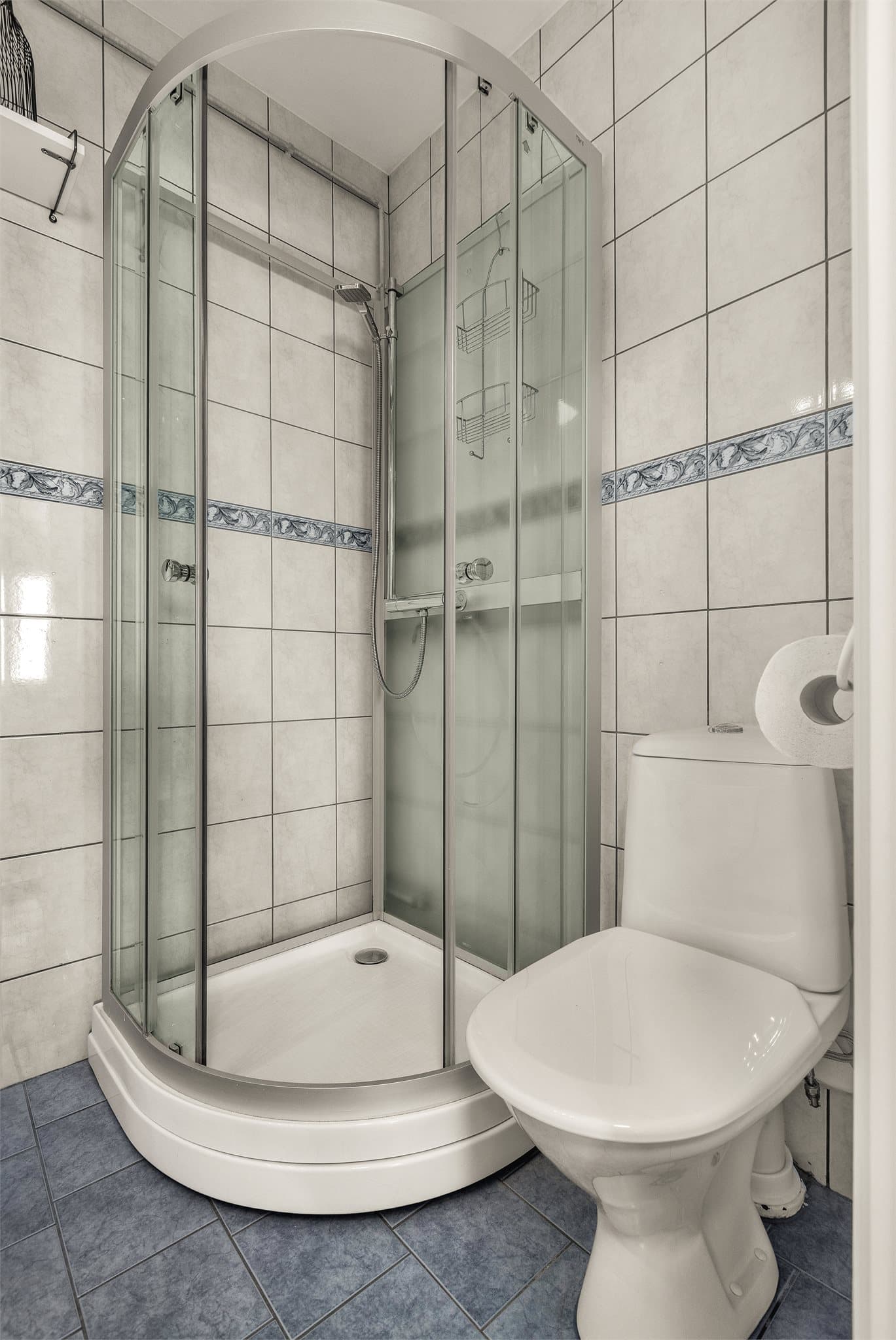 Badet har fliser på gulv og vegger, samt et eldre soilsluk.