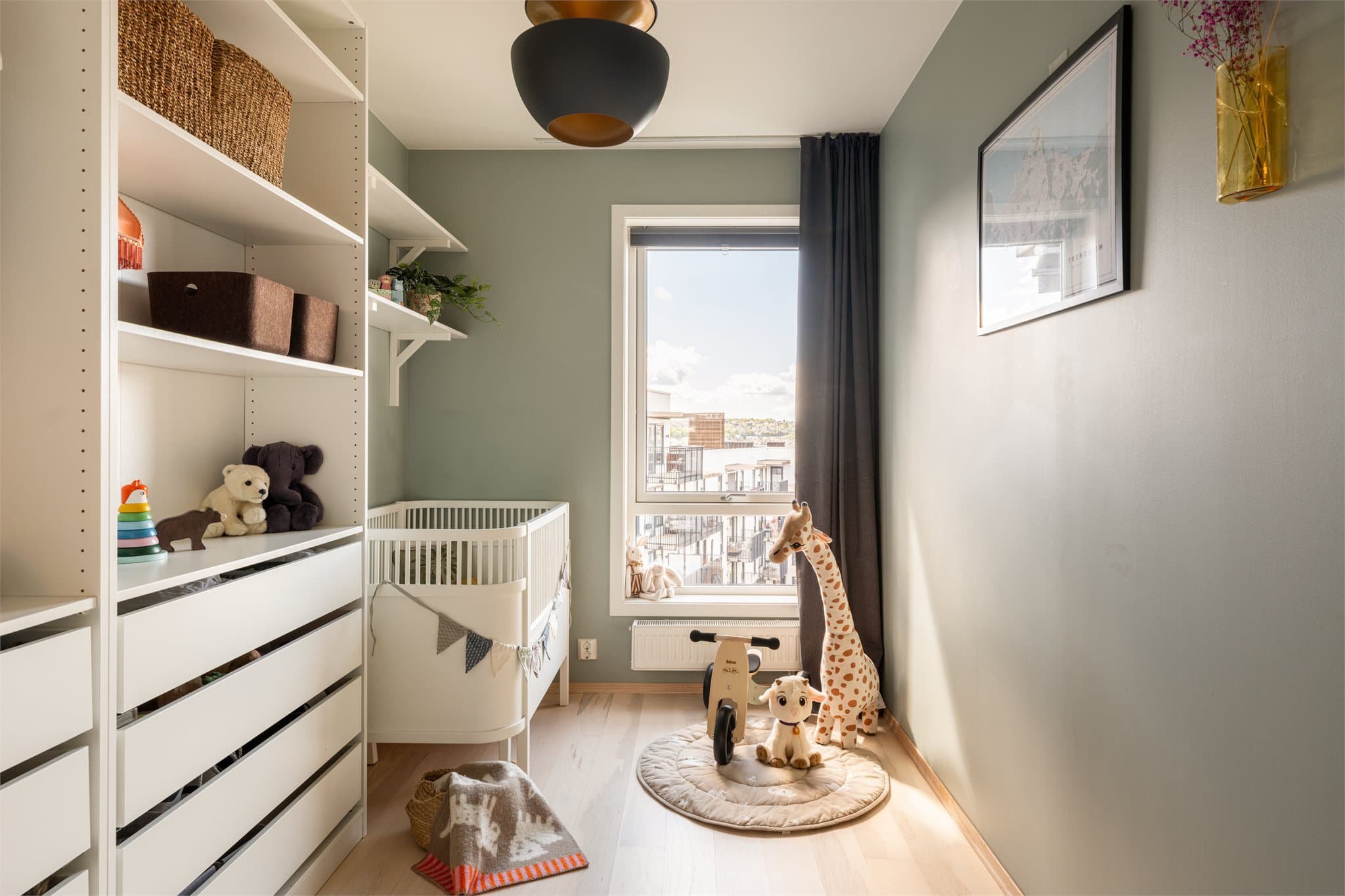Barnerommet har en lun atmosfære med duse fargetoner og fine lysforhold fra det store vinduet.