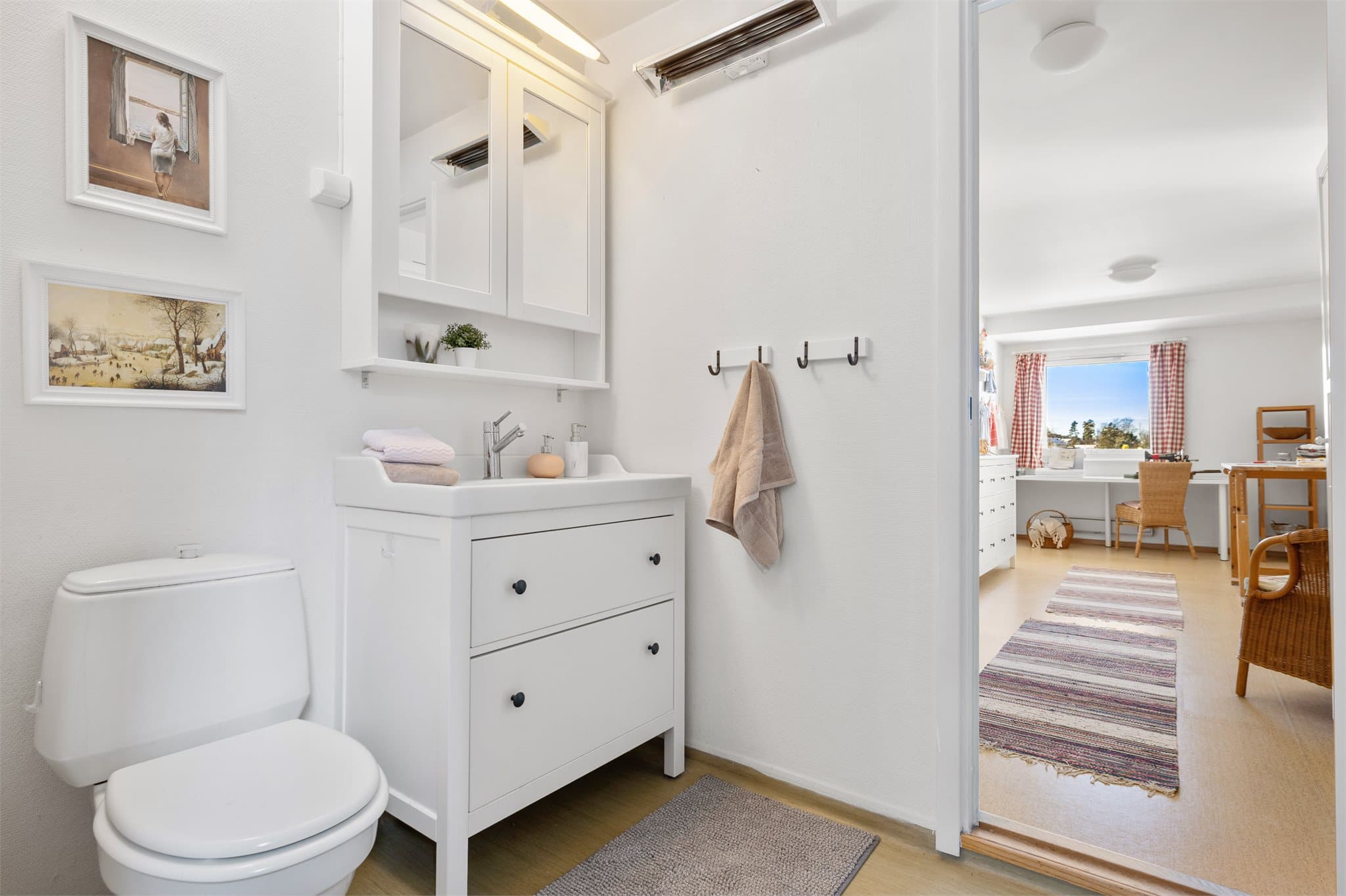 Easy access: Baderommet er lyst og funksjonelt med en gjennomtenkt planløsning. Her finner du stående klosett, praktisk servant på hvit baderomskommode med skuffer for god oppbevaring, og et speilskap med belysning som gir både lys og funksjon.