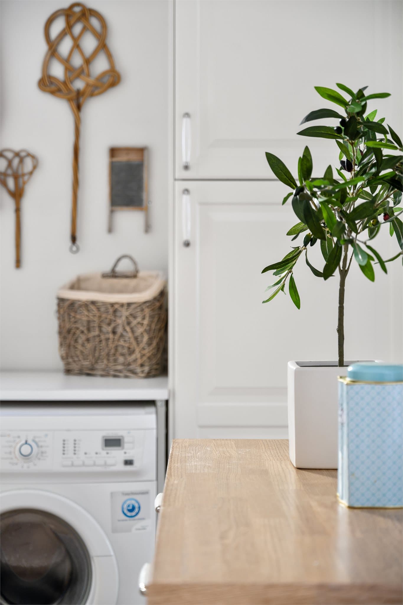 Da og nå: Et nostalgisk glimt fra vaskerommet – gamle teppebankere og et klassisk vaskebrett står stille i kroken, og minner om tidløs husholdningshåndverk midt i dagens praktiske vaskeløsning.