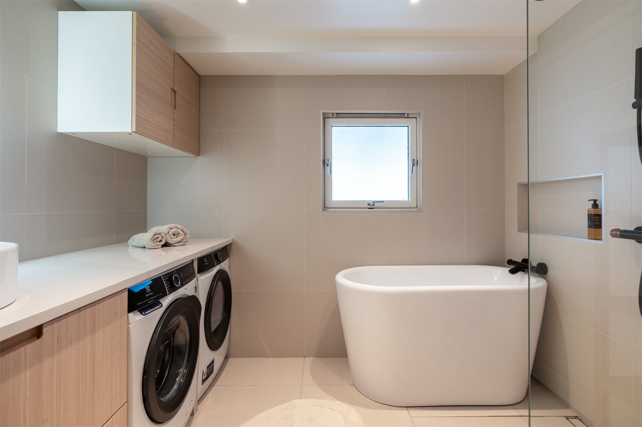 Svært delikat baderom med både badekar og dusj, samt praktisk opplegg for vaskesøyle under benkeplaten.