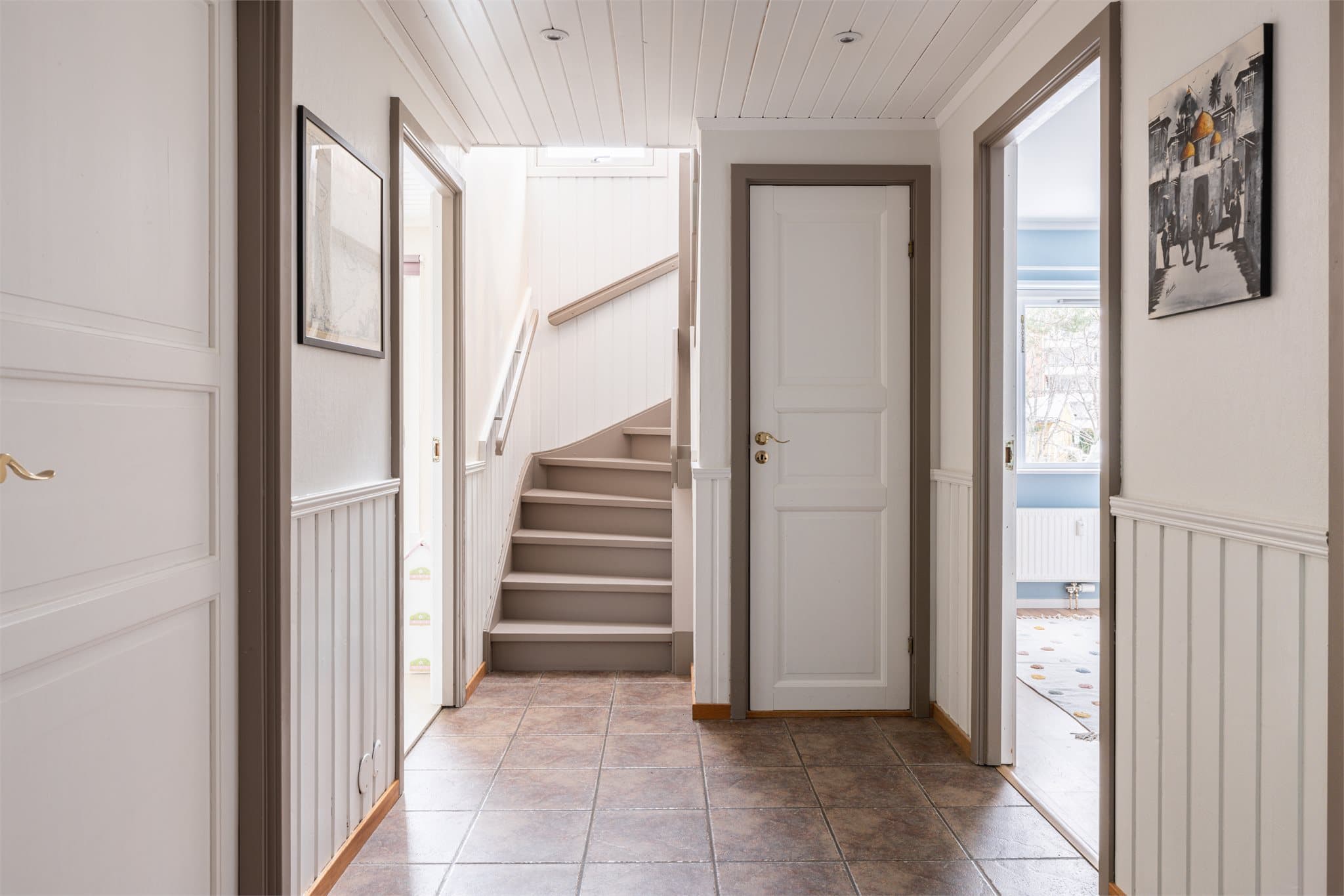 Gangen med downlights binder rommene sammen, og den nymalte trappen leder opp til andre etasje.