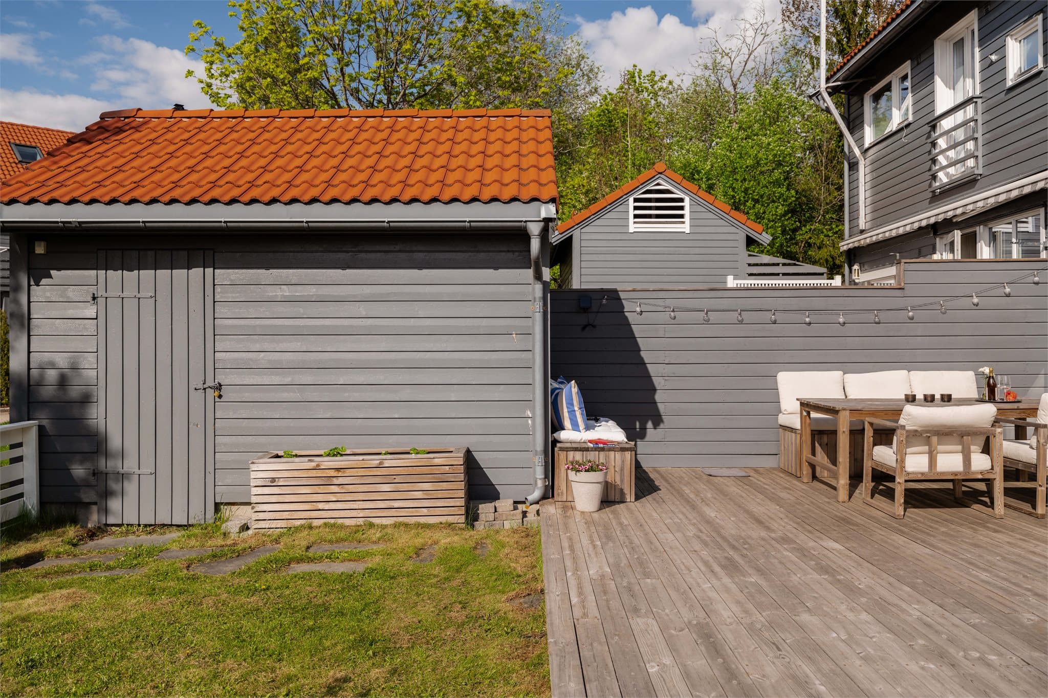 Uteplassen har en praktisk bod for oppbevaring av hageredskaper, sesongmøbler og leker for barna.