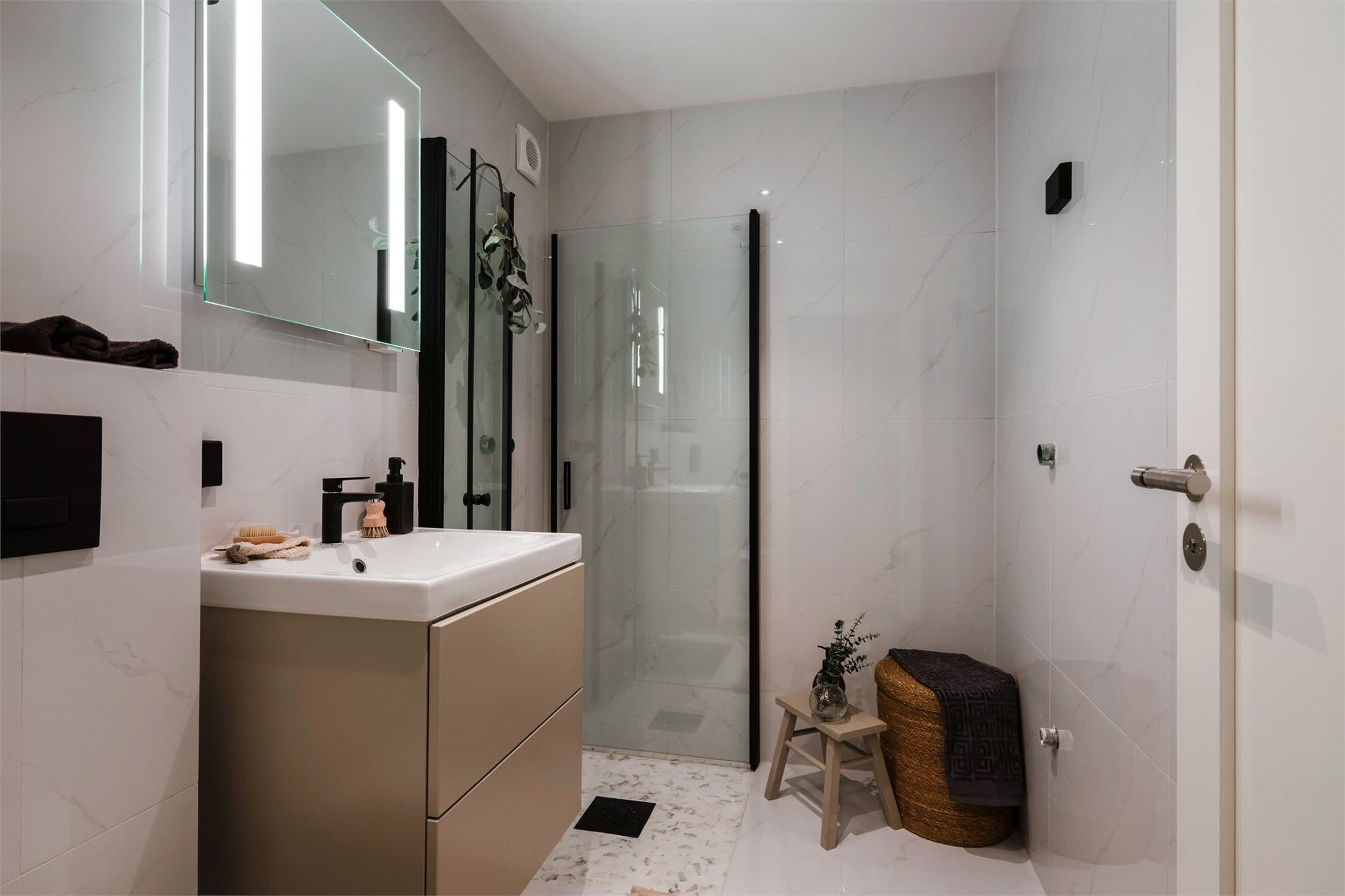 Delikat, flislagt bad fra 2025 med vegghengt toalett og servant med skuffeinnredning.