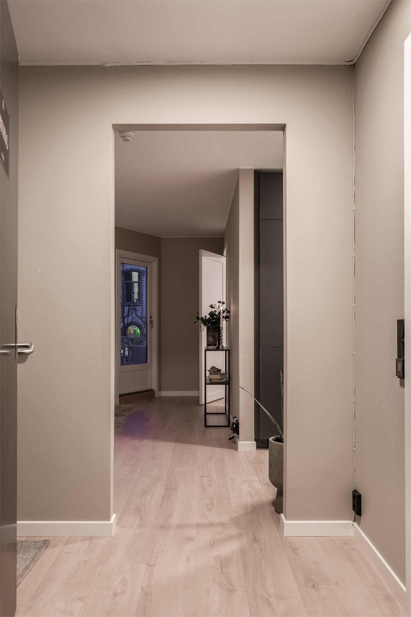 Fra entréen åpner leiligheten seg opp, med gjennomgående laminatgulv som skaper en helhetlig følelse.