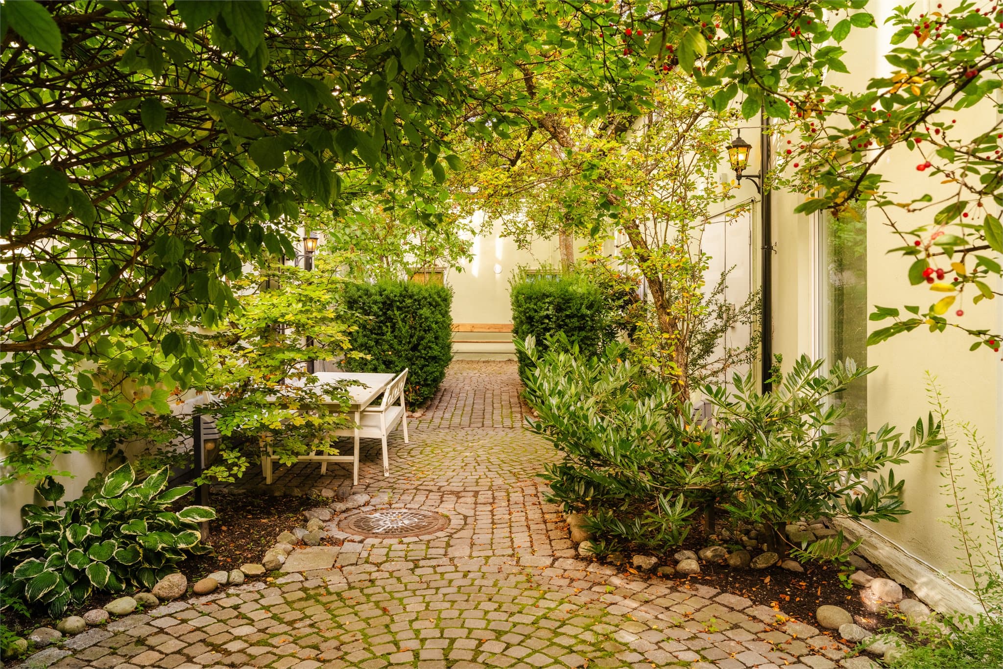 Det skjermede felles gårdsrommet har frodig beplantning, sitteplasser og brosteinsbelagte gangveier.