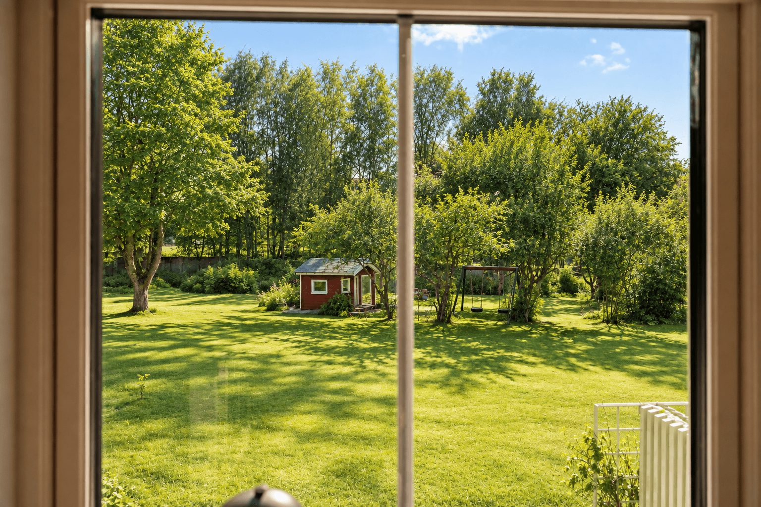 Fra leiligheten er det flott utsyn mot borettslagets rolige og grønne fellesarealer. Bildet er redigert med hjelp av kunstig intelligens fra vinter til sommerbilde.