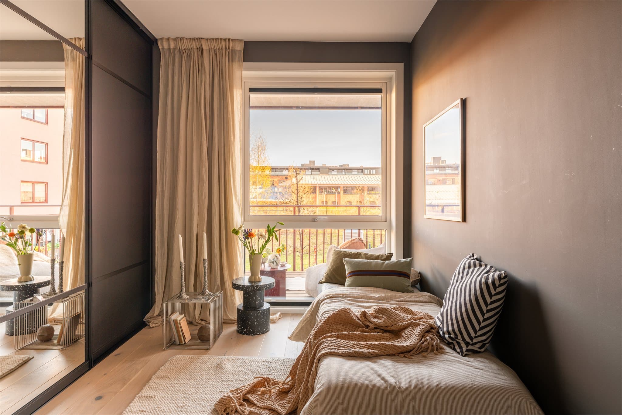 Store vinduer slipper inn rikelig med naturlig lys, mens mørke vegger gir rommet et lunt preg. Det er montert innvendig solskjerming på vinduene.